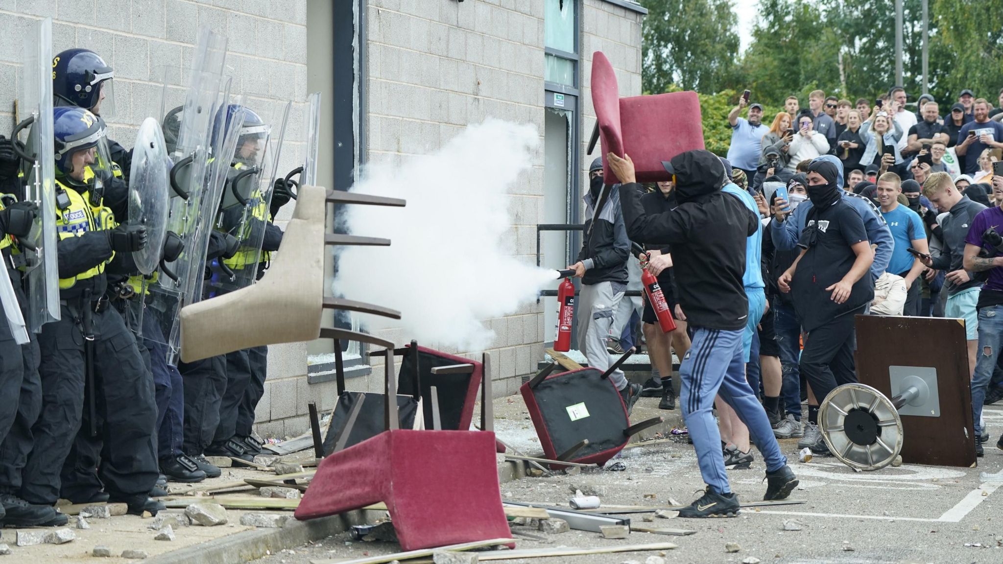 Protester holding up chair in front of police