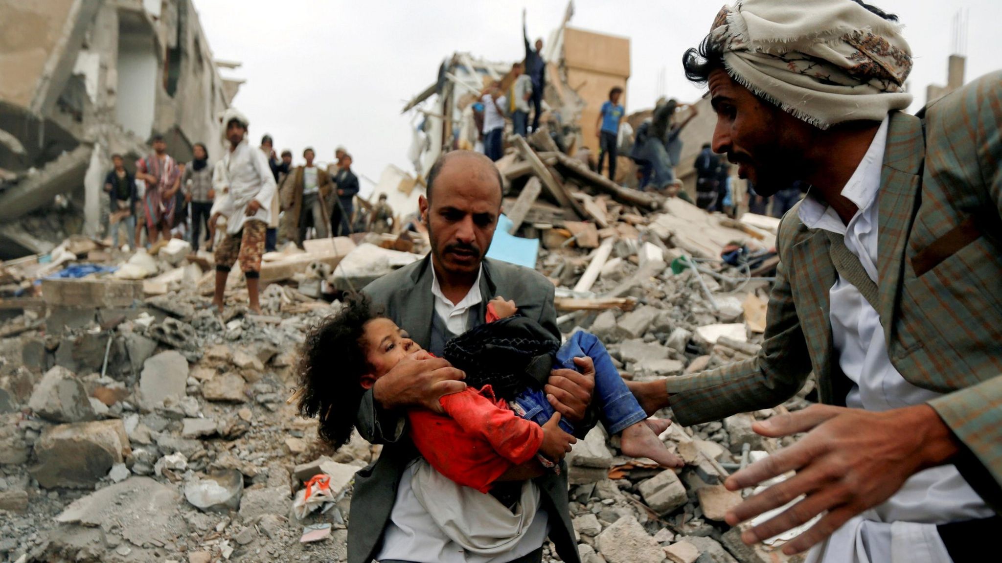 A man carries a girl rescued from the site of a suspected Saudi-led air strike that killed eight members of her family in Sanaa, Yemen (25 August 2017)