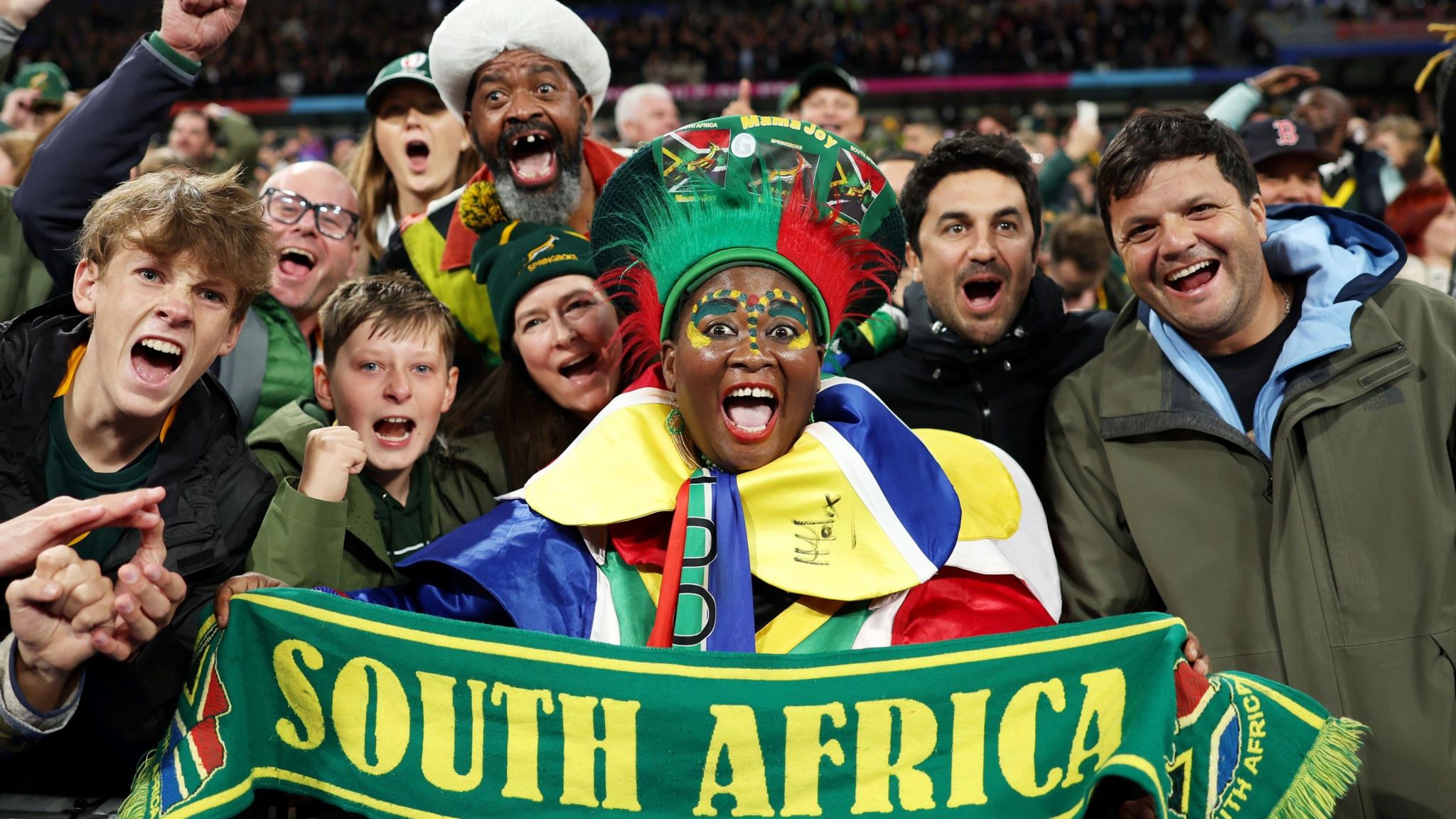 Superfan Mama Joy holds up a scarf that says South Africa on it among fans at the 2023 Rugby World Cup in France