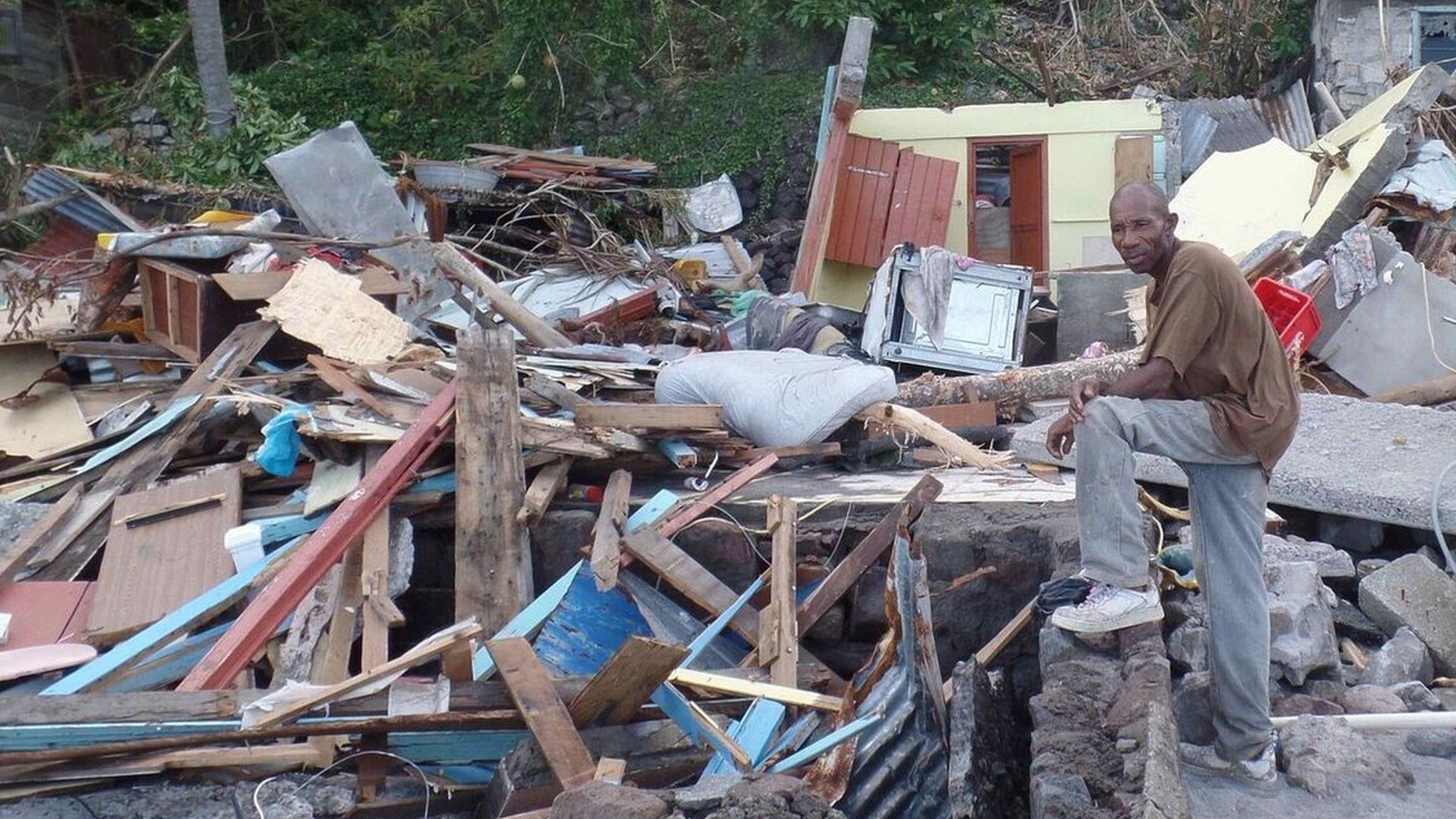 A man stands by the ruins of a home in Dominica