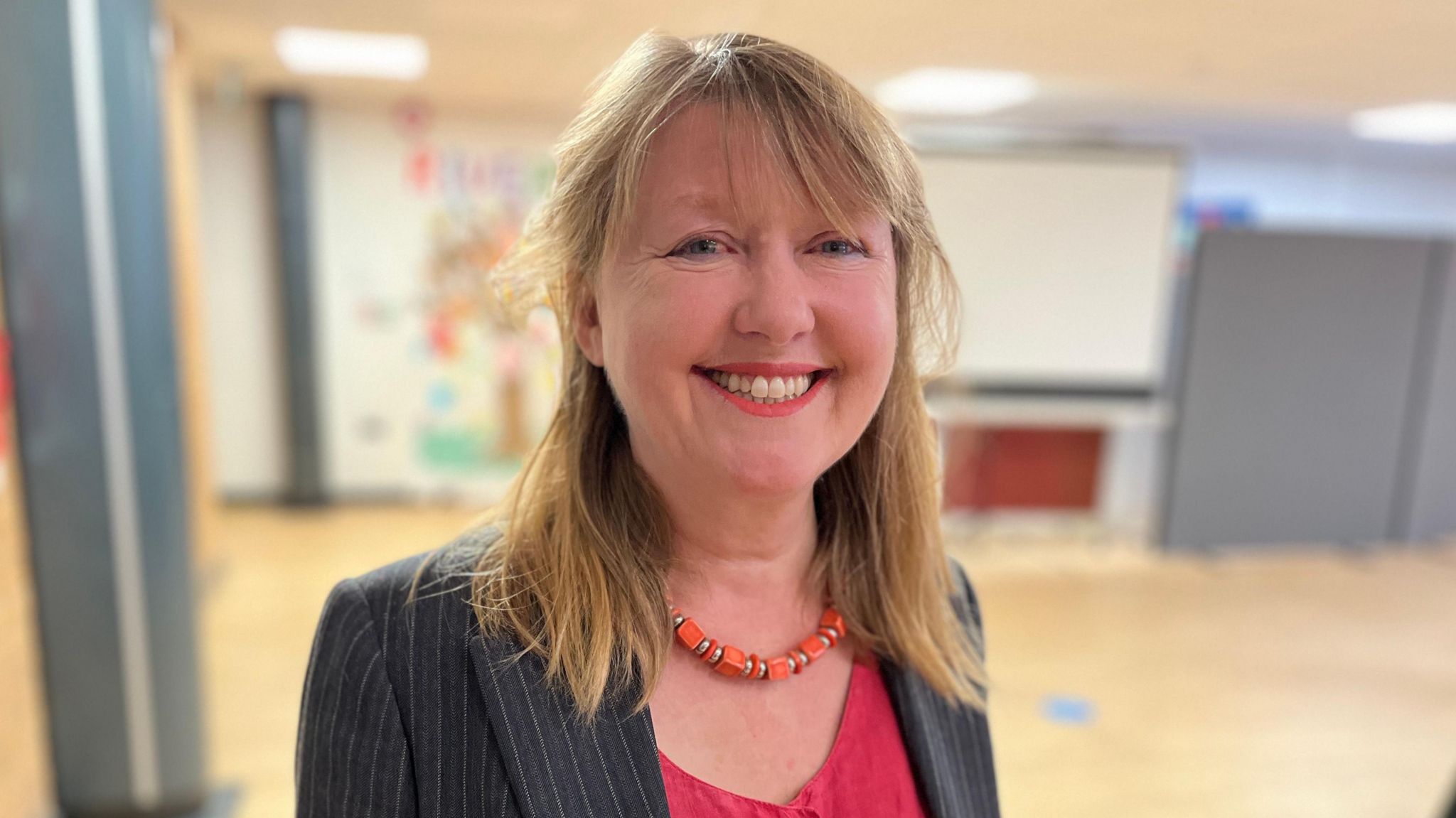 Chippenham MP Sarah Gibson smiling at the camera. She is wearing a red top, and a dark blazer with grey stripes