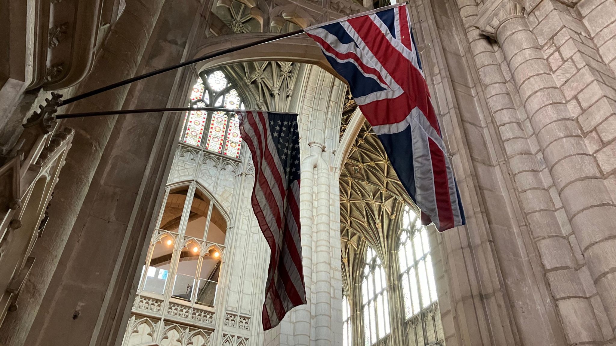A British flag and US flag hanging beside each other in Gloucester Cathedral