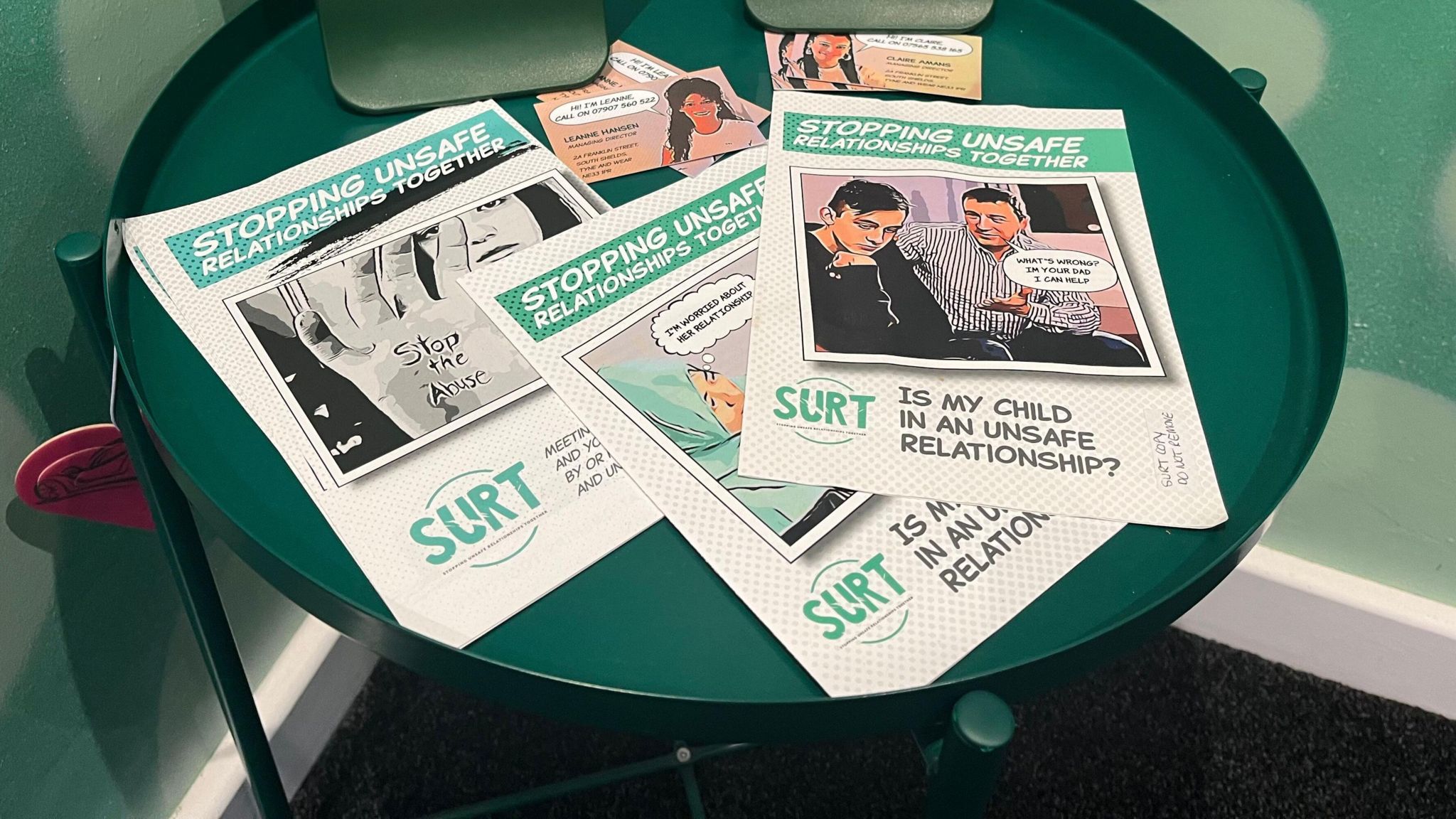 Leaflets laid out on a green coffee table offering advice on stopping unsafe relationships