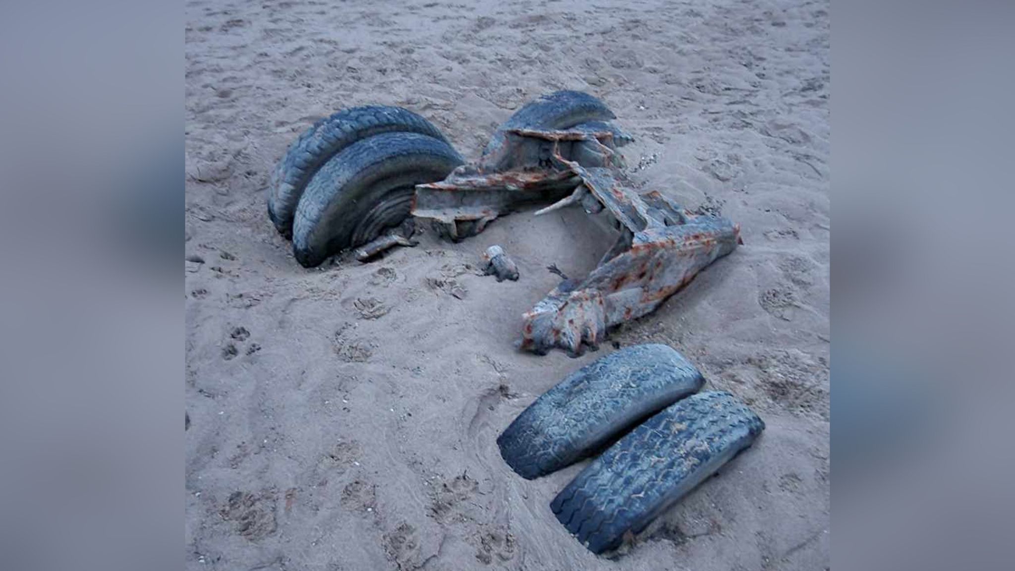 A truck with four wheels partly buried in the sand