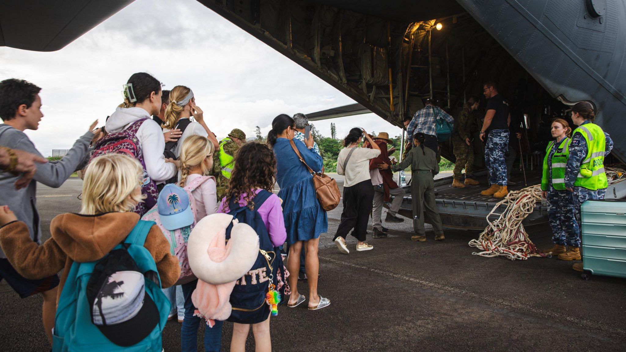 A line of tourists board an Australian military plane in New Caledonia