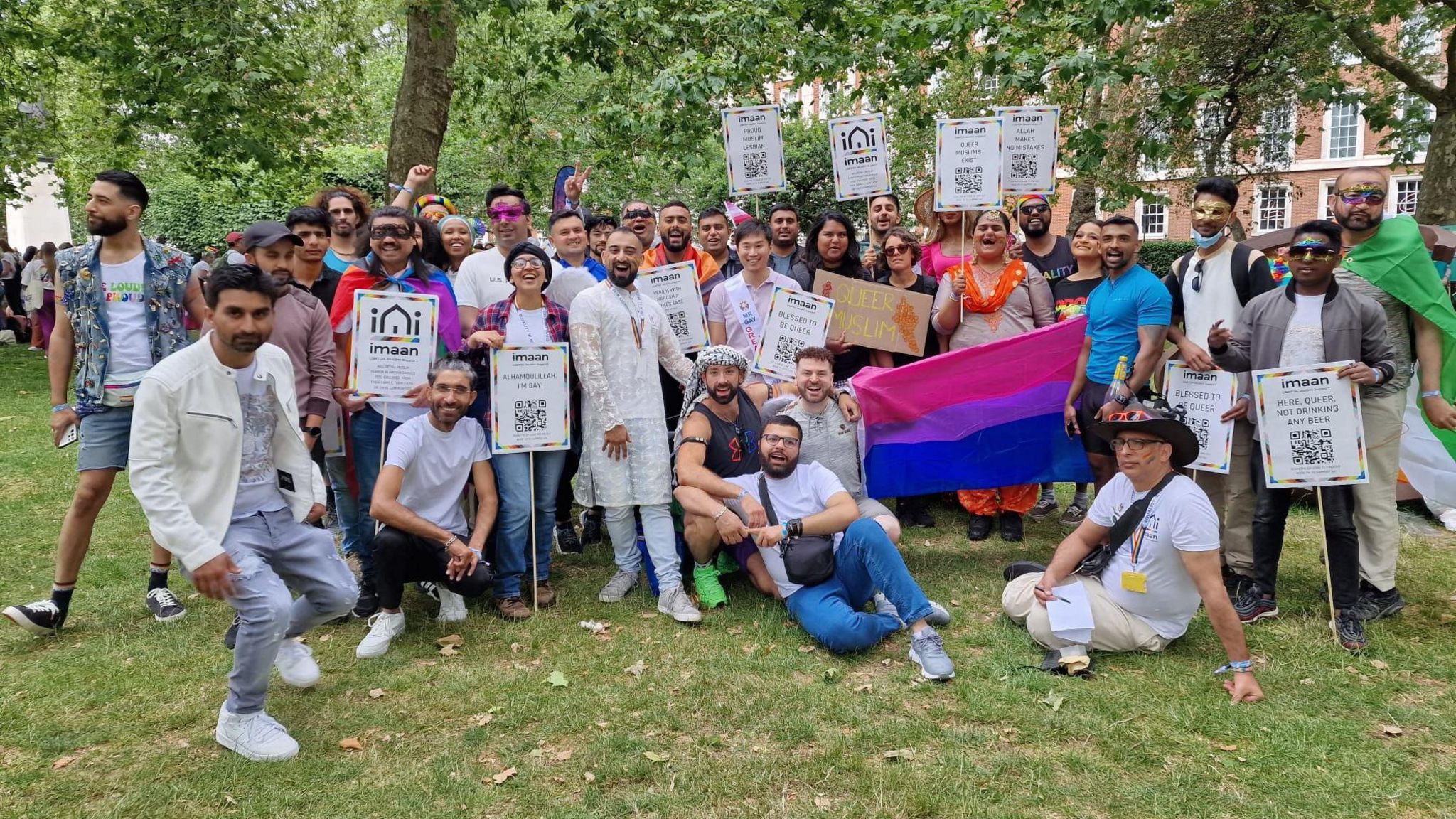 A group of members of Imaan LGBTQI+ gathered on a grassy area, holding placards and flags at Pride in London last year