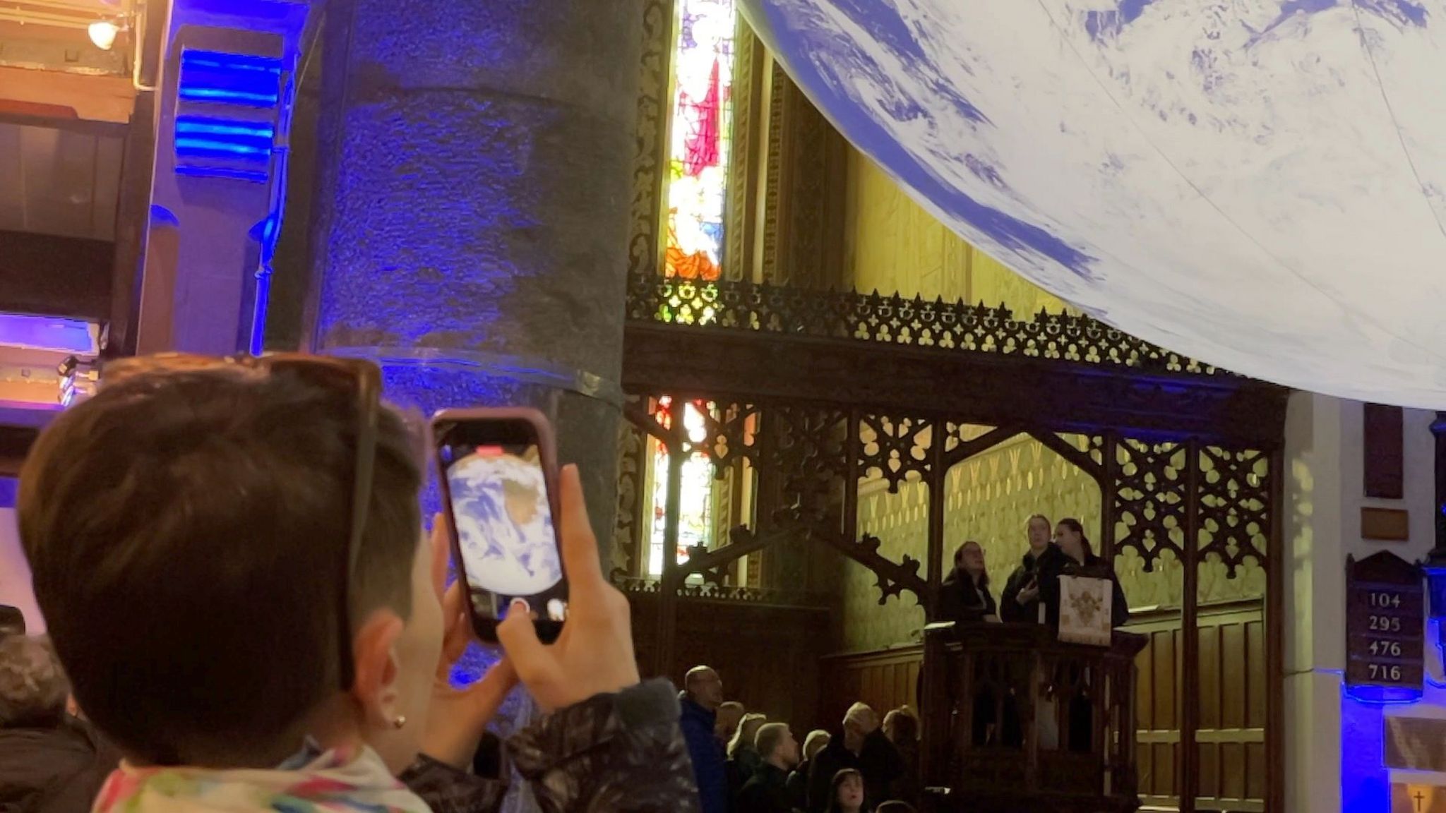 A woman taking a photo of Gaia in St Thomas' Church