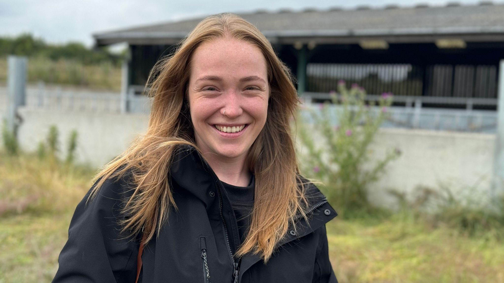 A woman standing in front of a cattle shed