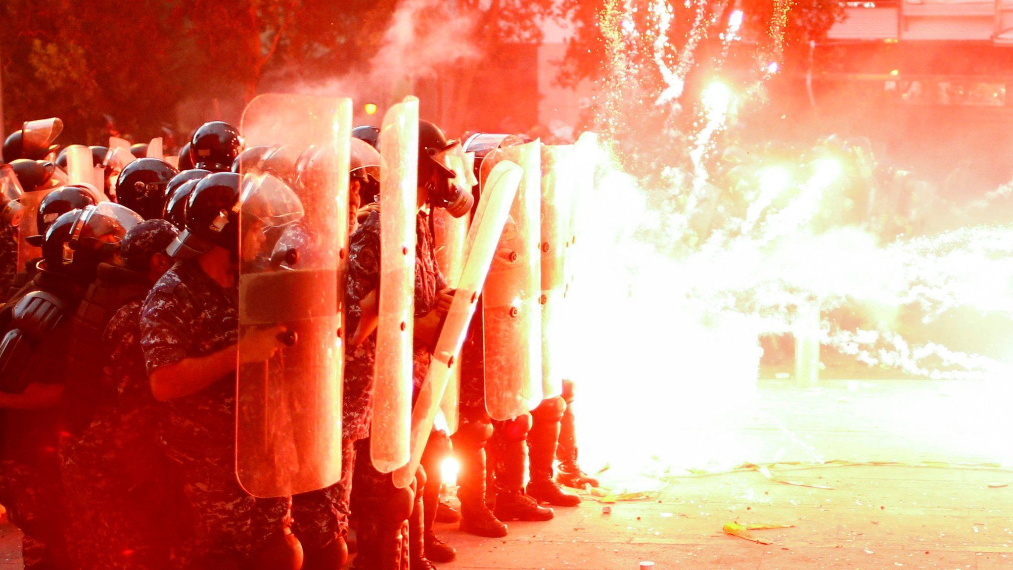Fireworks launched by anti-government protesters hit the shields of riot police officers in Beirut on 10 August 2020