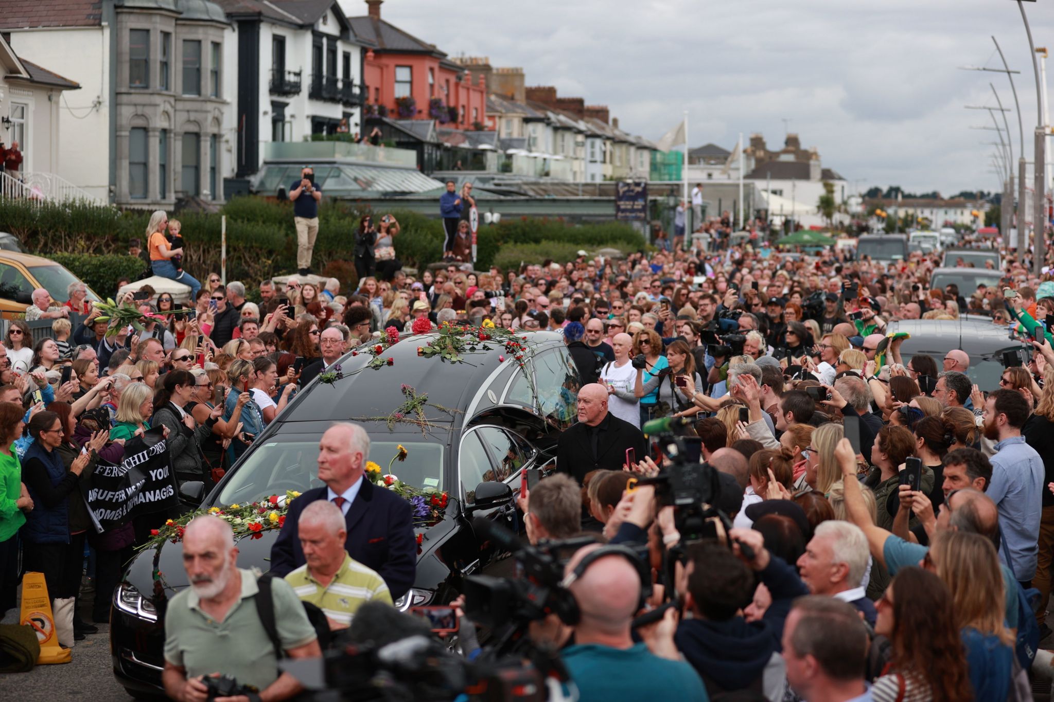 A hearse passes through a crowd