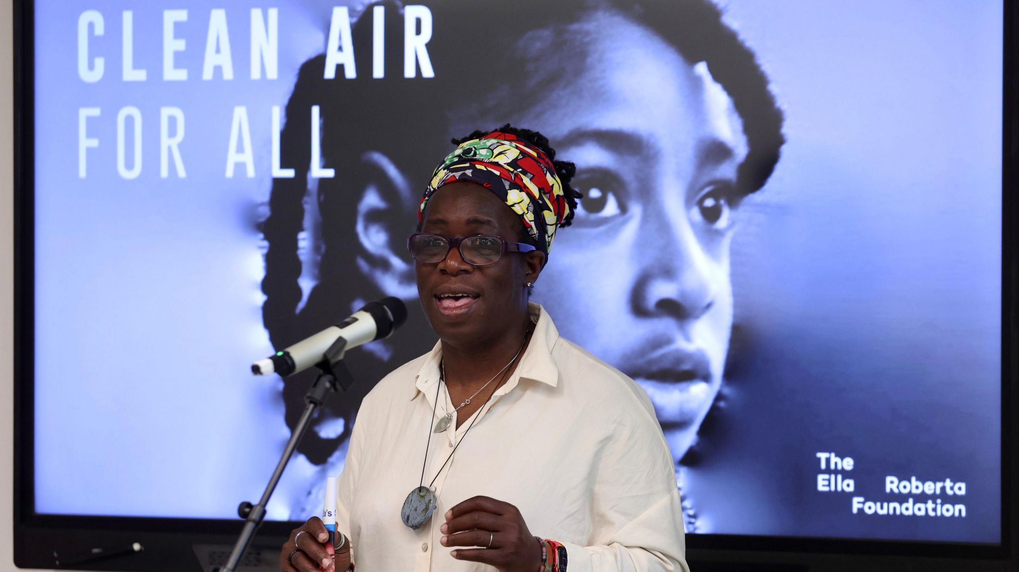 Rosamund Adoo-Kissi-Debrah speaking in front of an image of her daughter Ella