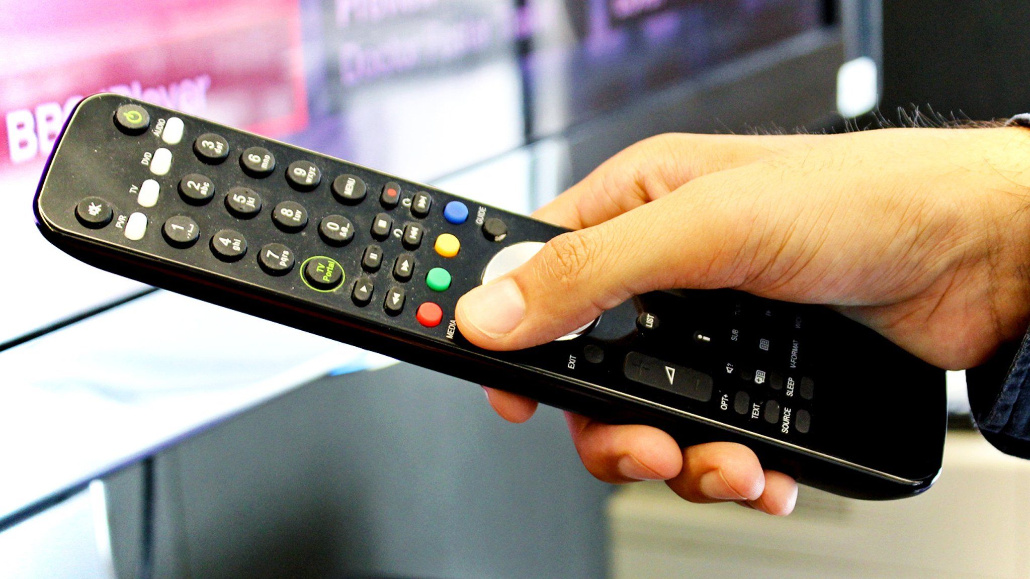 Person using red button on TV remote control
