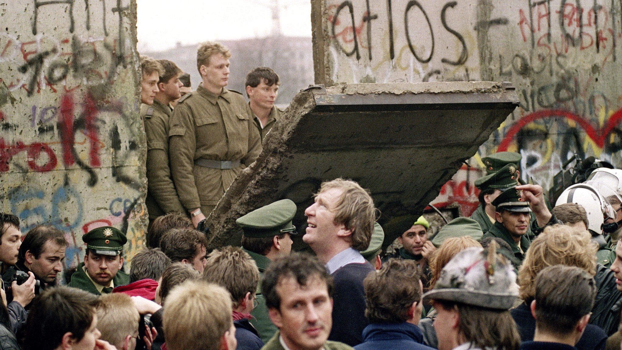West Berliners crowd in front of the Berlin Wall early 11 November 1989 as they watch East German border guards demolishing a section to open a new crossing point between East and West Berlin