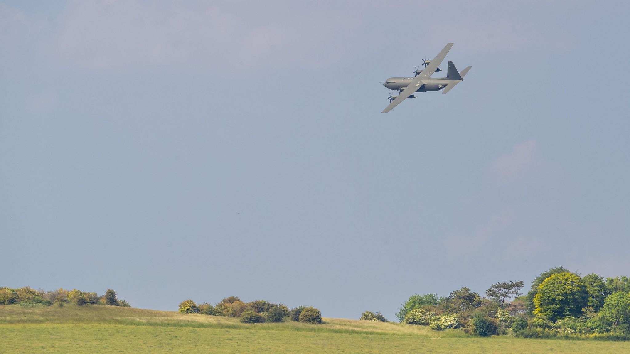 Hercules aircraft flying over fields at Boscombe Down