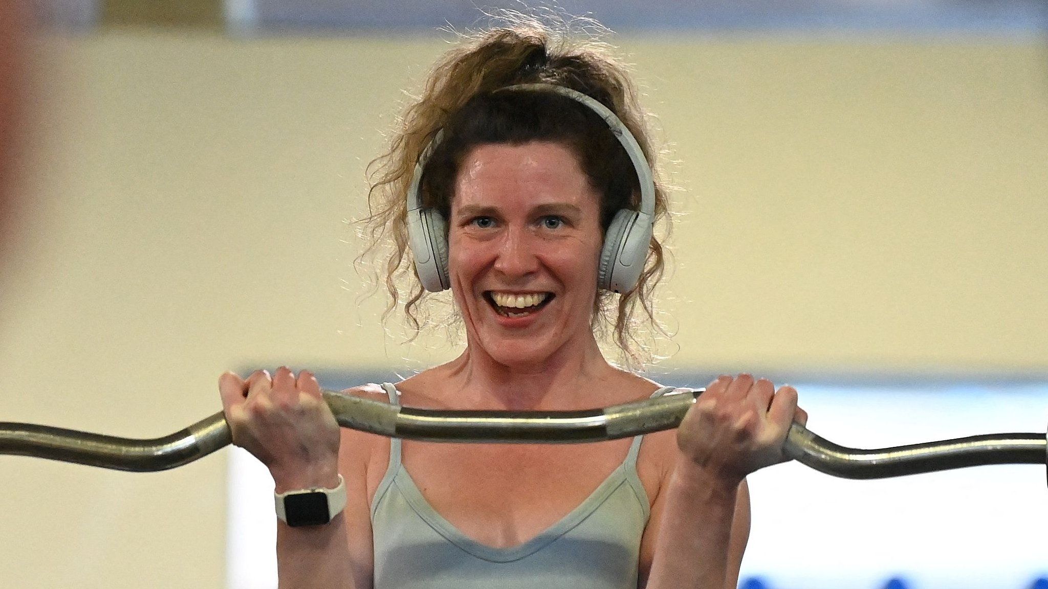 A woman lifts a weight whilst smiling at herself in the mirror