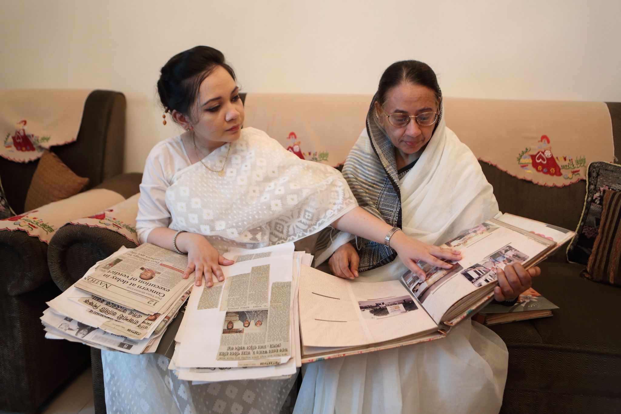 Shagufta and her mother looking at newspaper clippings recording their legal struggle