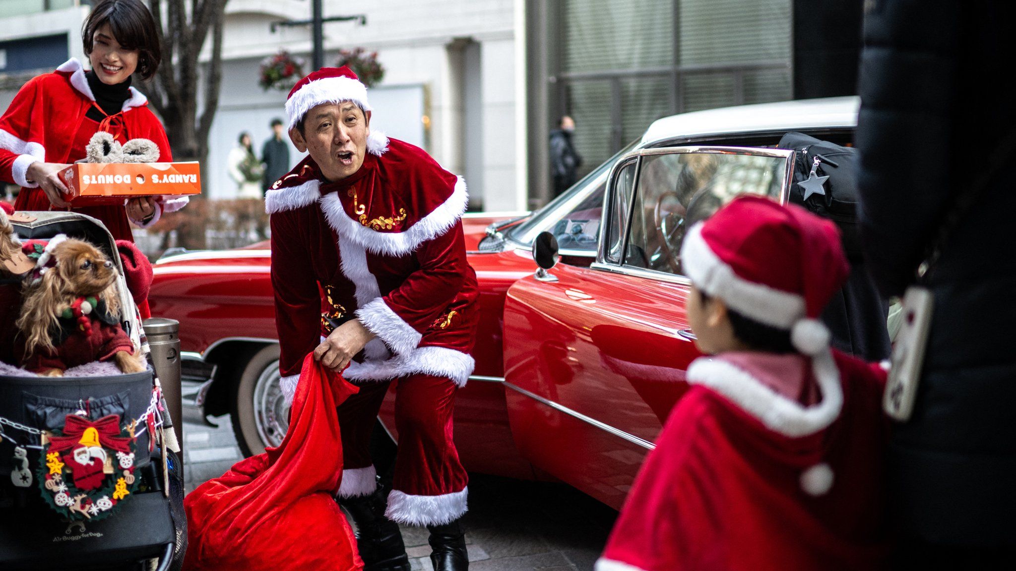 Membru al unui grup de mașini de epocă Hiroyuki Wada (C), îmbrăcat în Moș Crăciun, dă cadouri de Crăciun unui copil pe o stradă din zona Marunouchi din Tokyo
