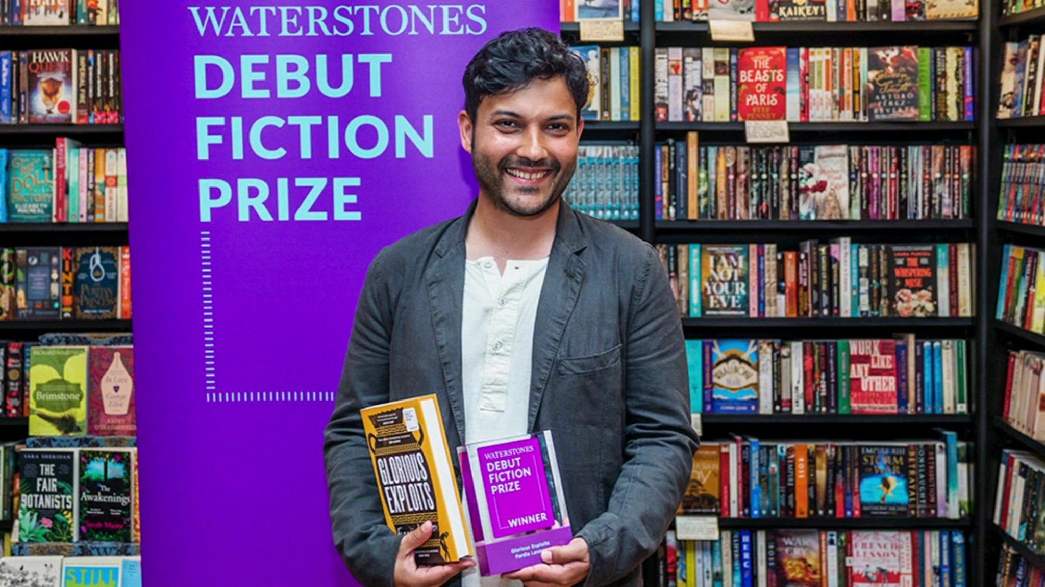 Ferdia Lennon wearing a blazer and holding his debut novel and award