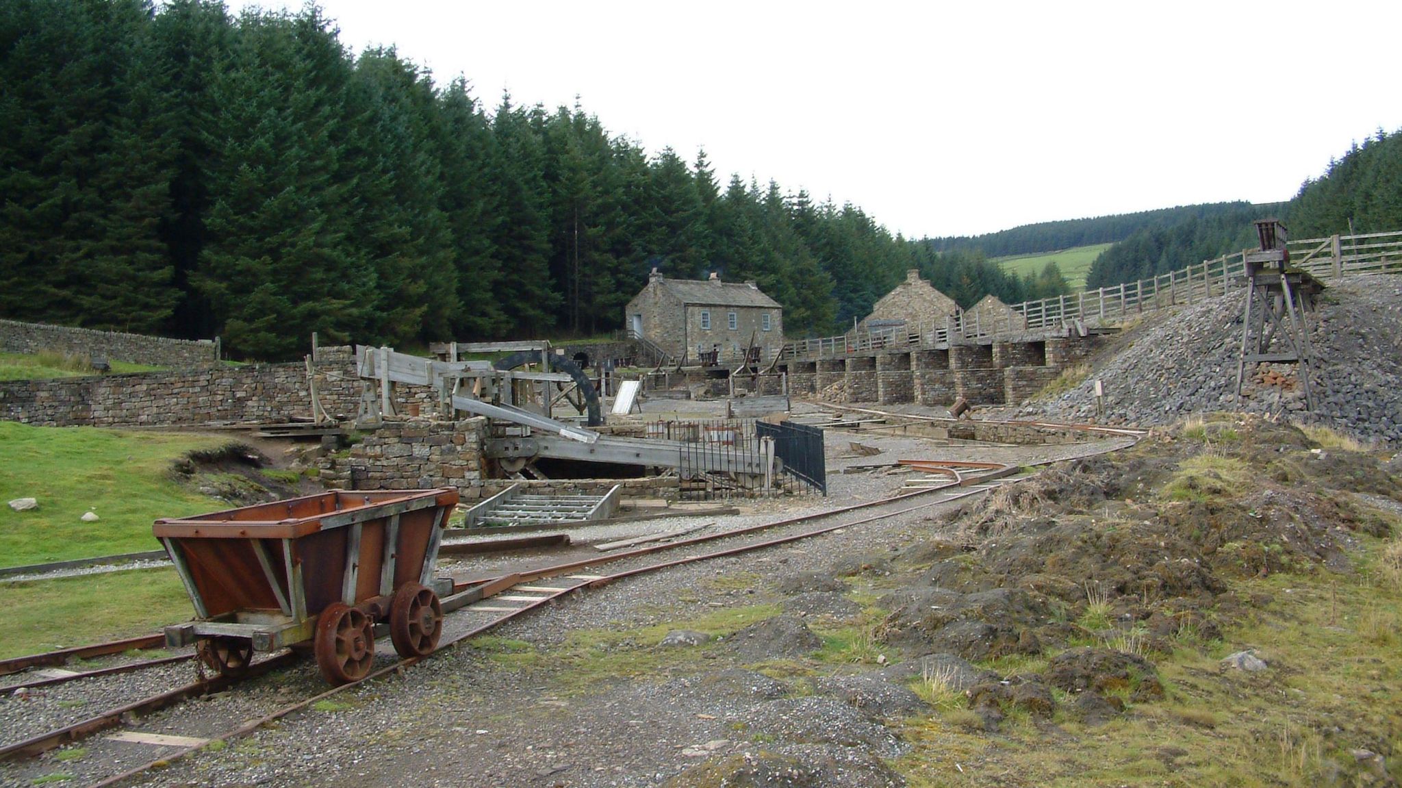 A restored mine with a wagon in the foreground and mine buildings behind