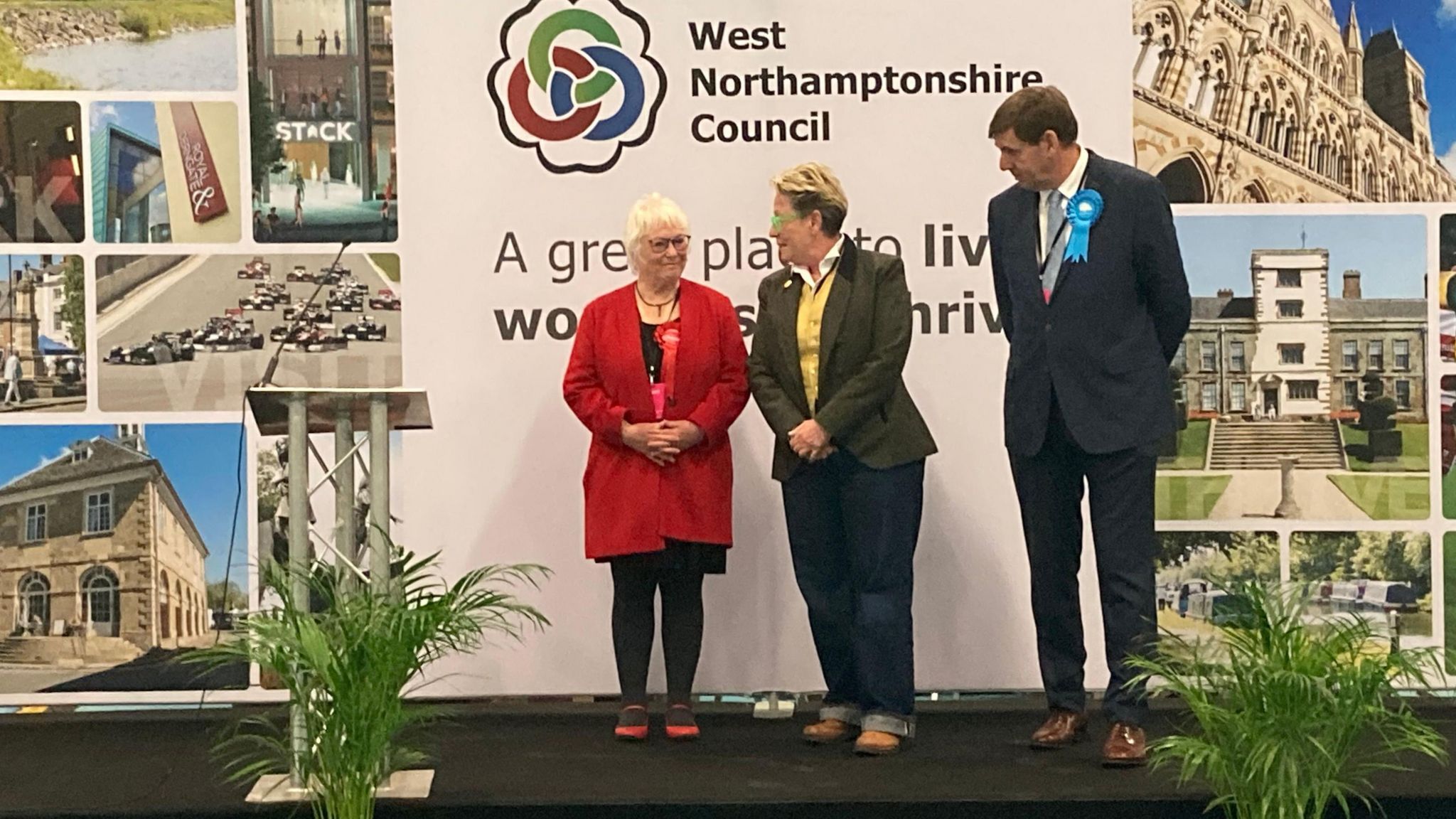Three candidates standing on stage at the count