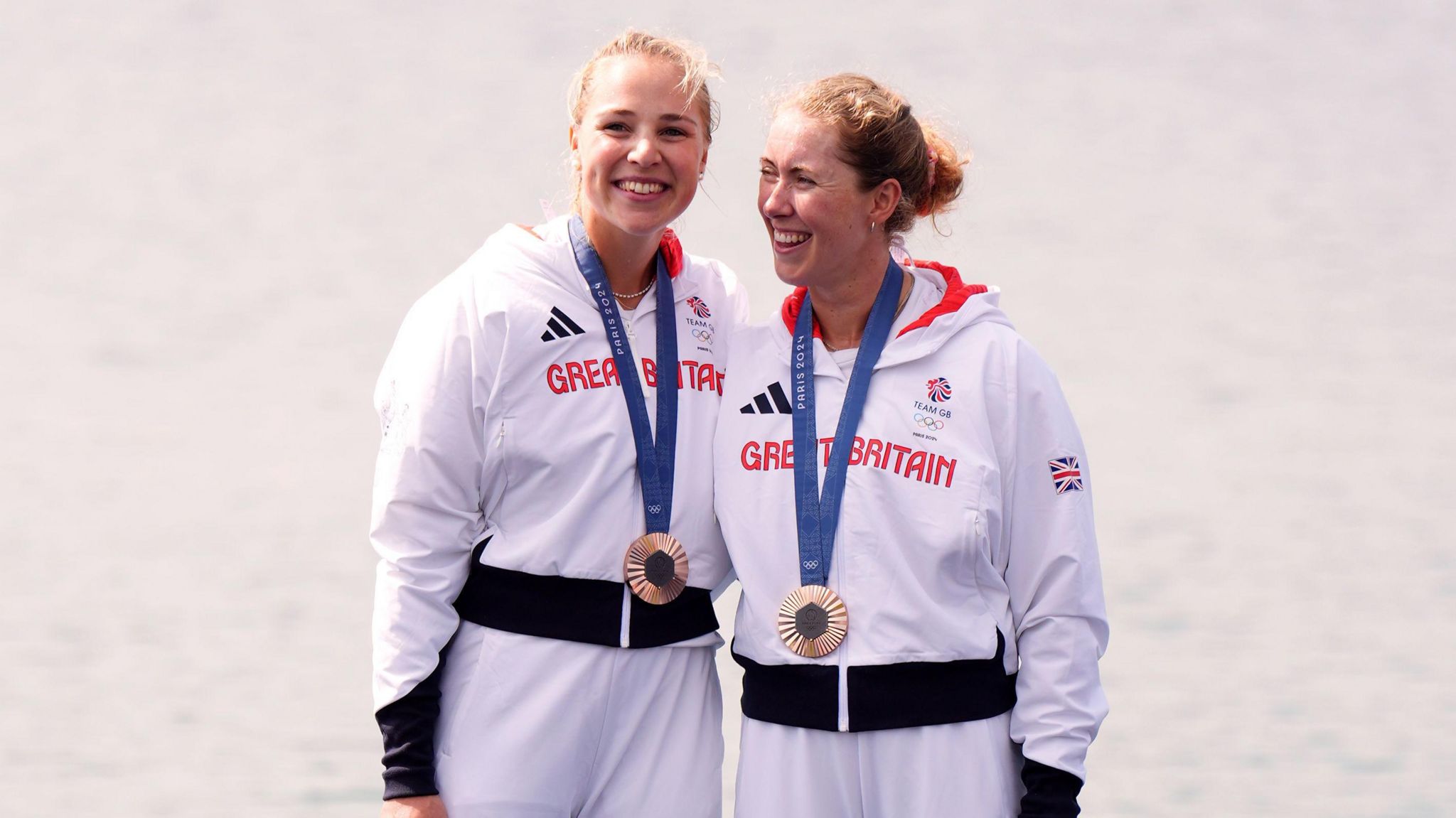 Rebecca Wilde and Mathilda Hodgkins-Byrne. They are both blonde and pictured wearing white Adidas jackets with Great Britain printed across the chest in red letters. They both have their medals around their necks and are smiling.  