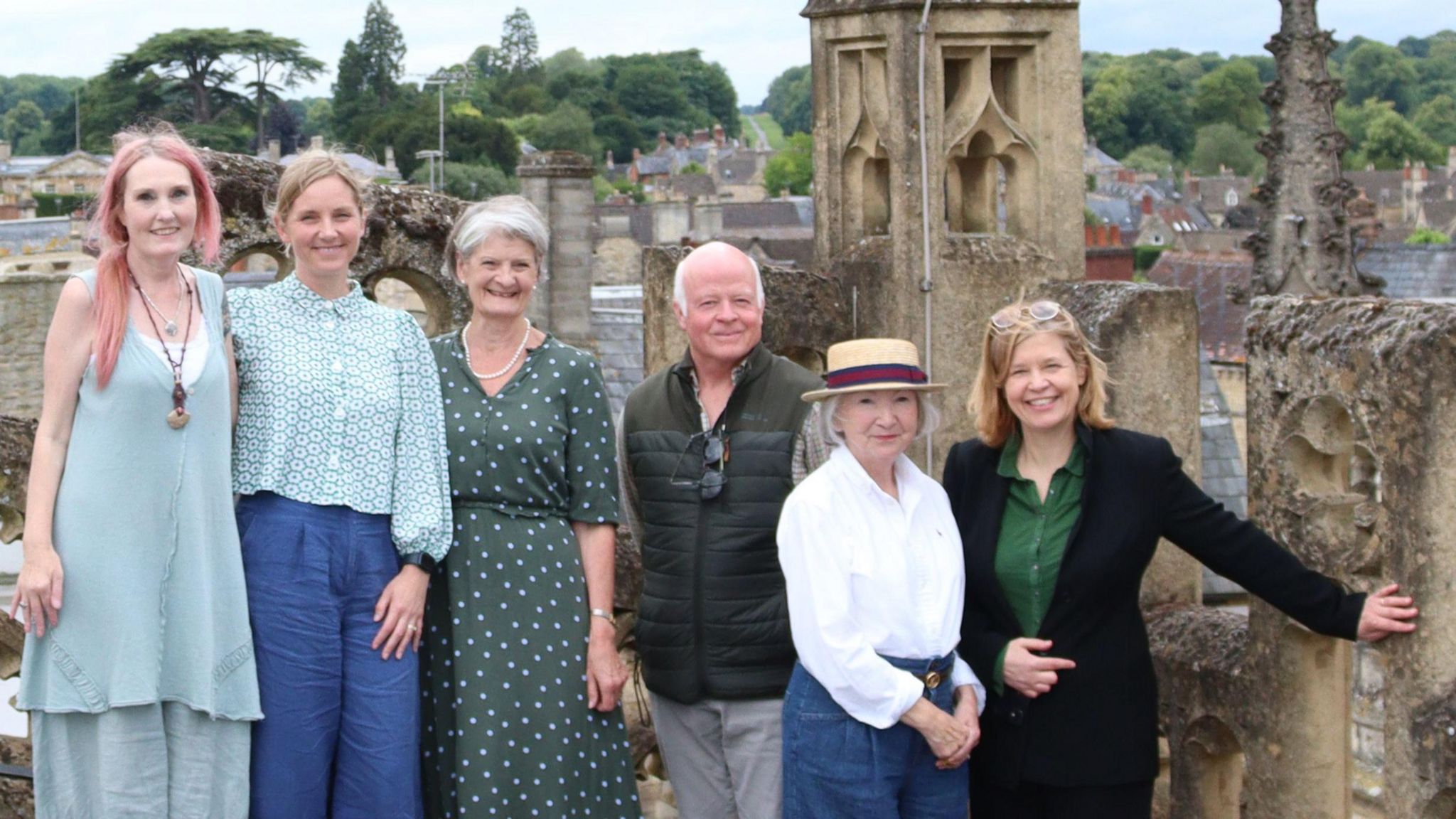 The six members of the committee standing on top of a church next to its spires