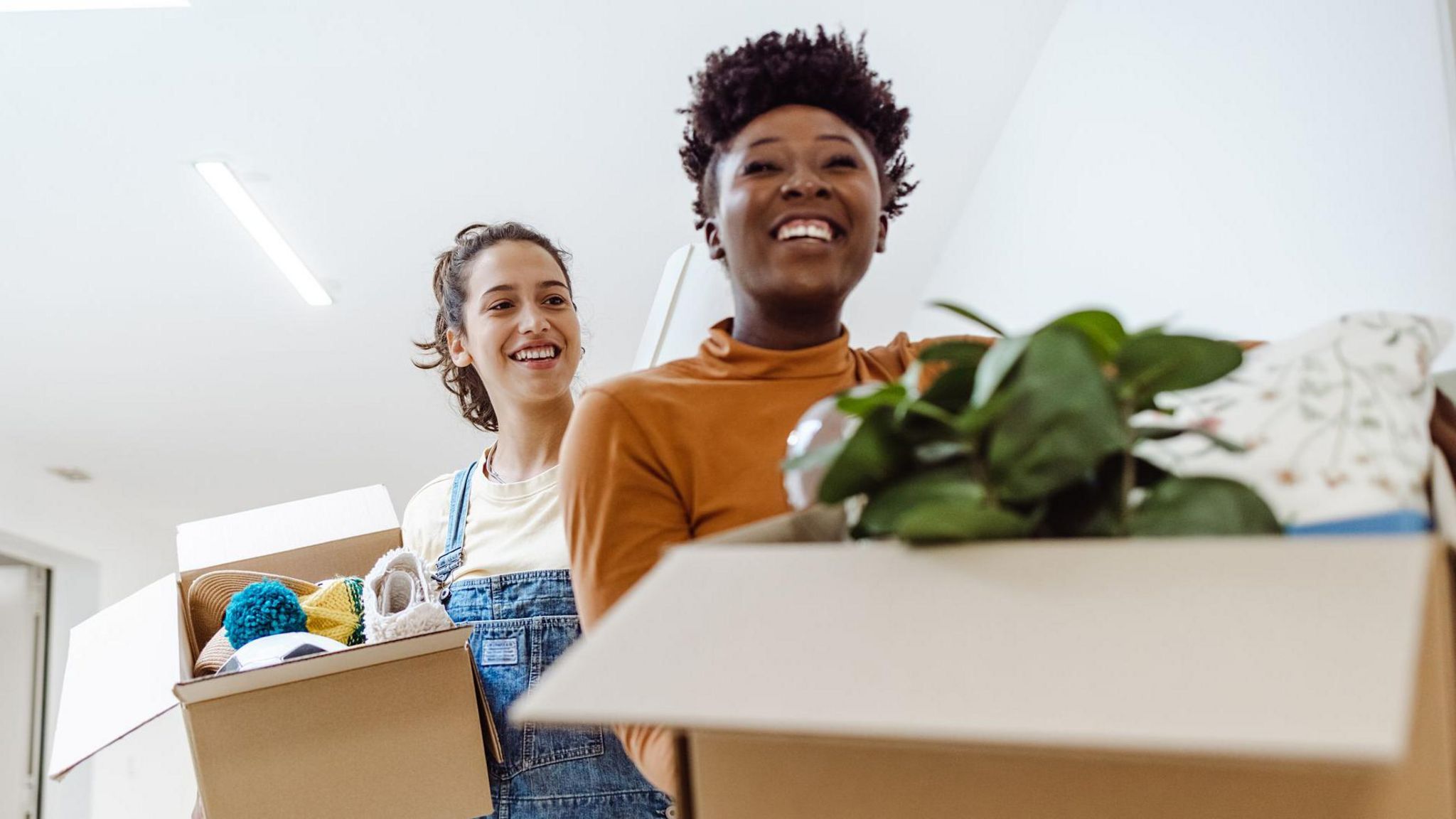 Two students smile as they hold boxes of belongings