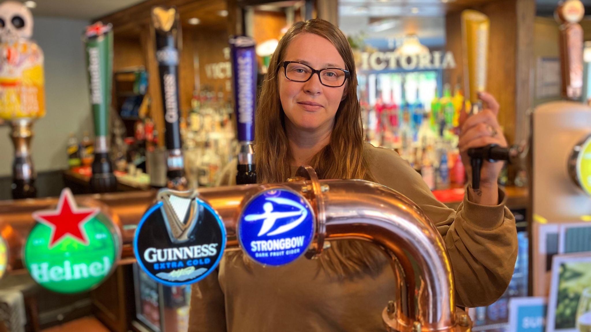 Kirsty Jones operator of The Victoria standing at the bar with beer taps visible