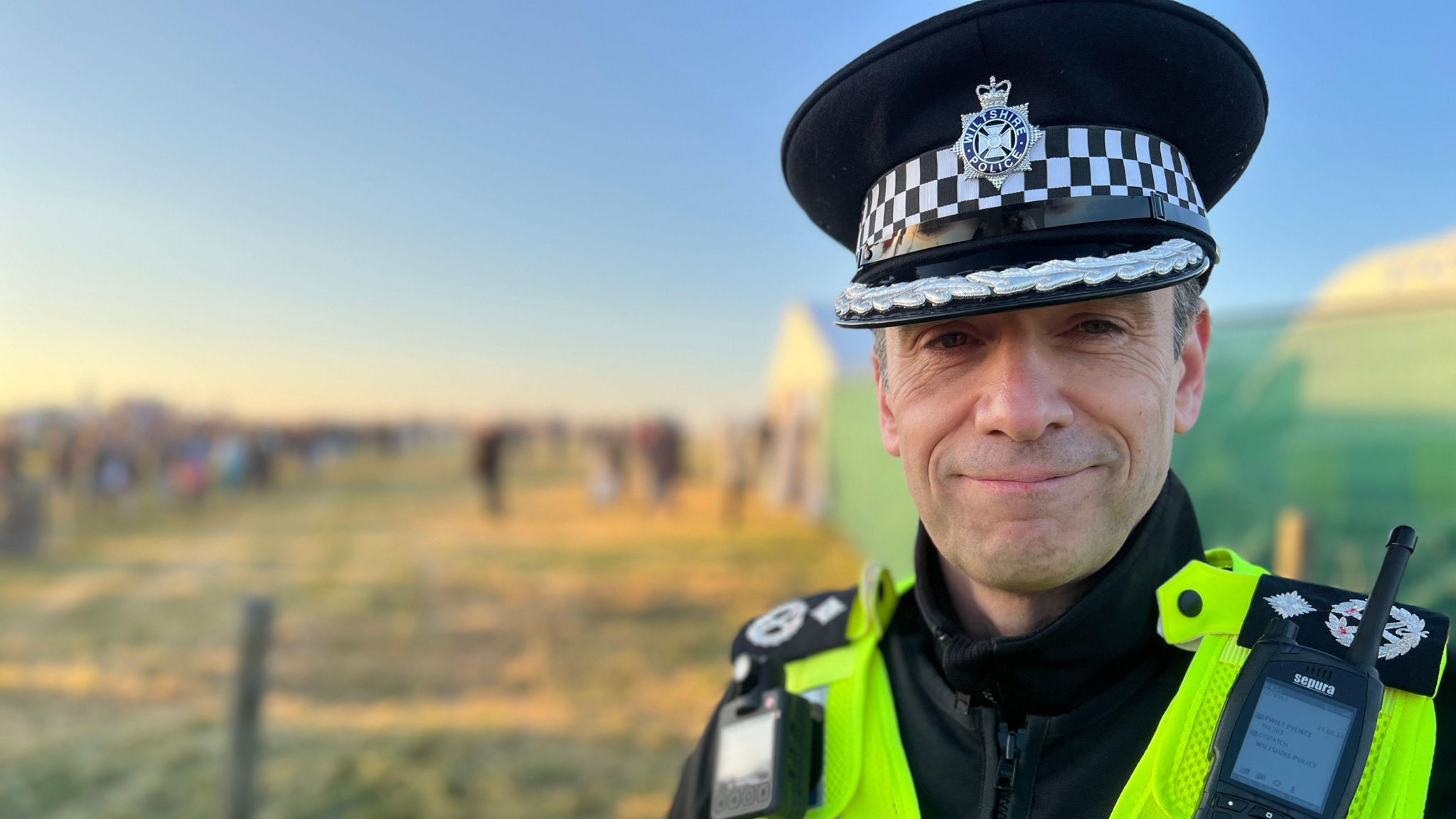 Craig Dibdin looks at the camera in police uniform, including radio, hat and high-vis