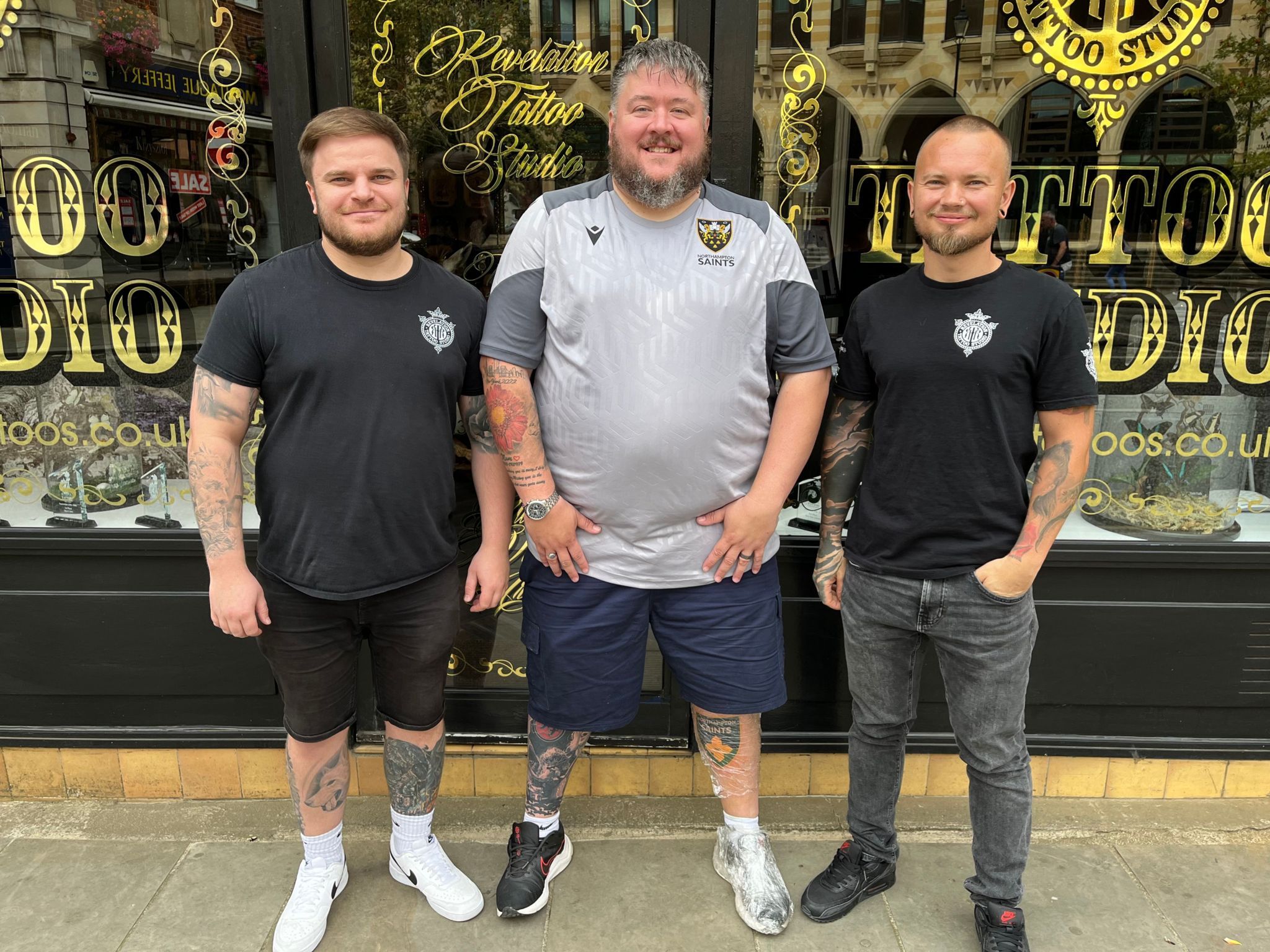 Tattoo studio manager Phil Bennett, Simon Stacey and tattoo artist Lorand Szacaks standing outside the gold-lettered window of the Revelation Tattoo Studio in Northampton