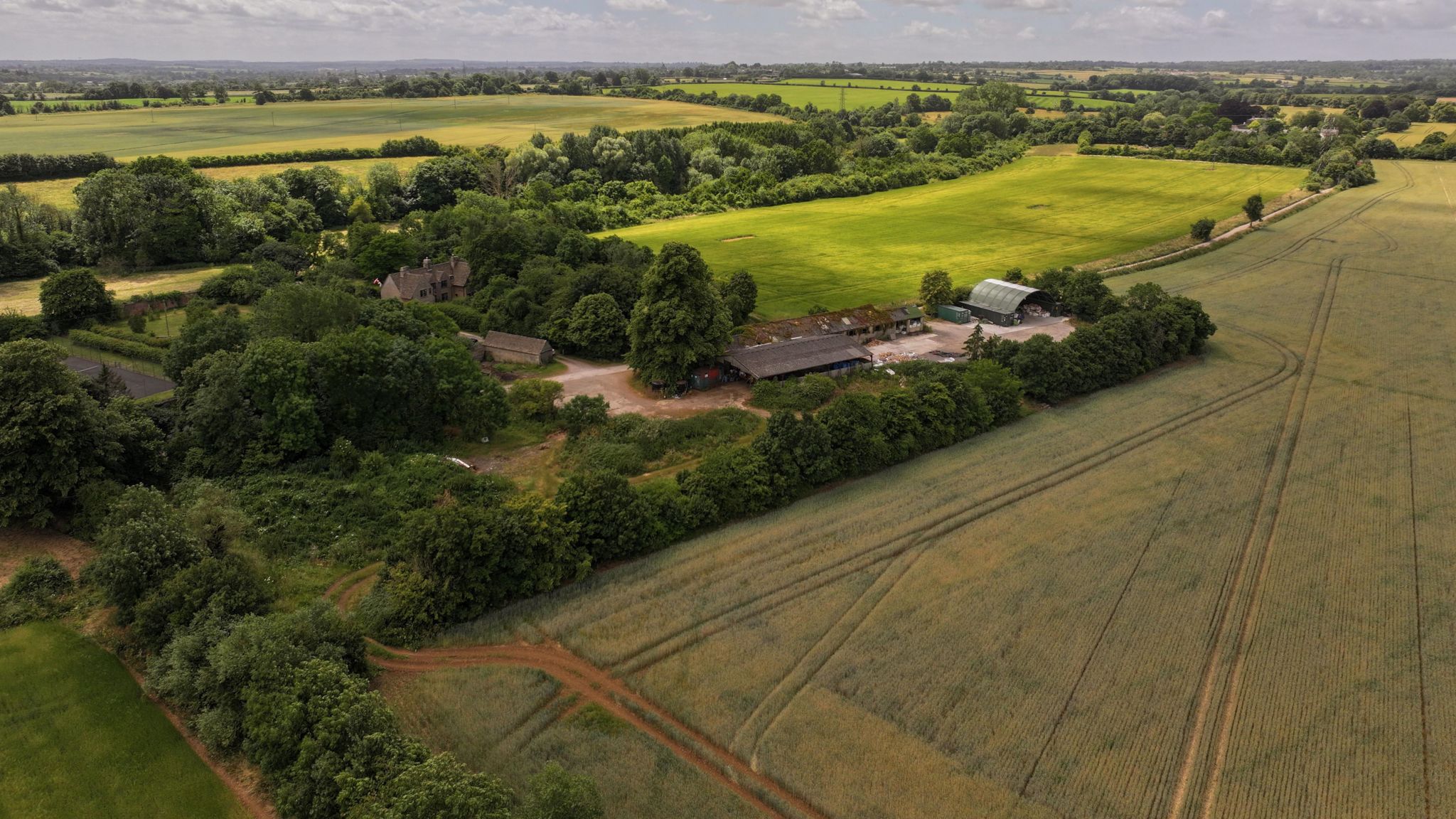 Drone shot of farming land with trees and fields on a sunny day