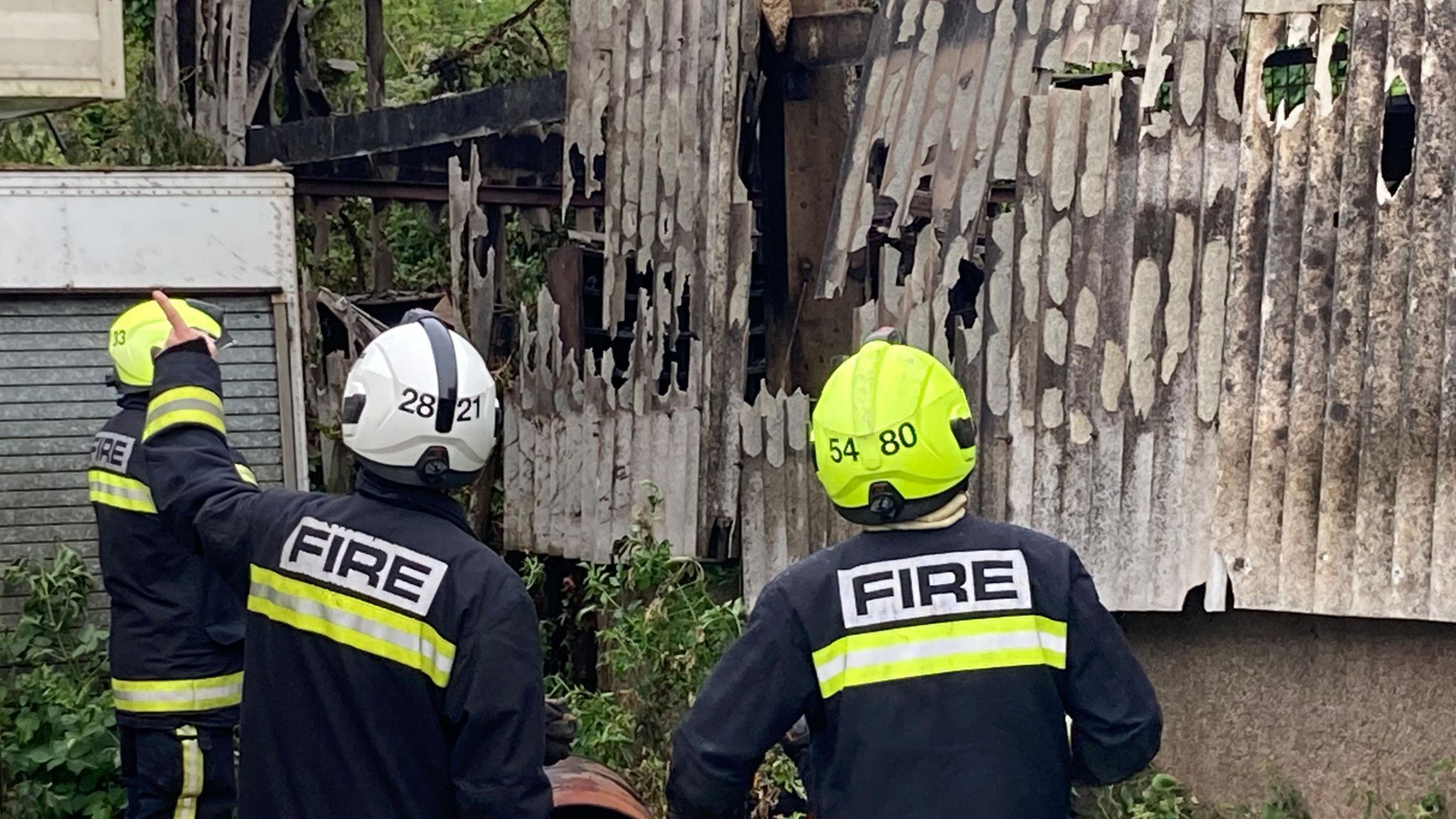 Three fire fighters examining the damage to the workshop near Poltimore