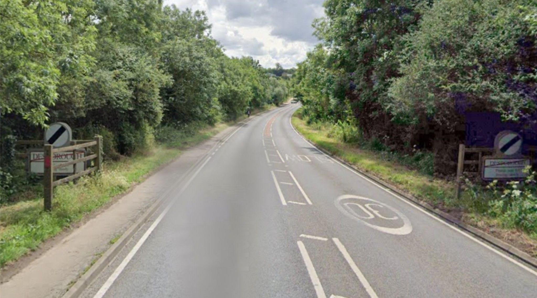 Road leaving Desborough, with the town name shown on both sides. A national speed limit sign is visible. A child is walking in the distance.