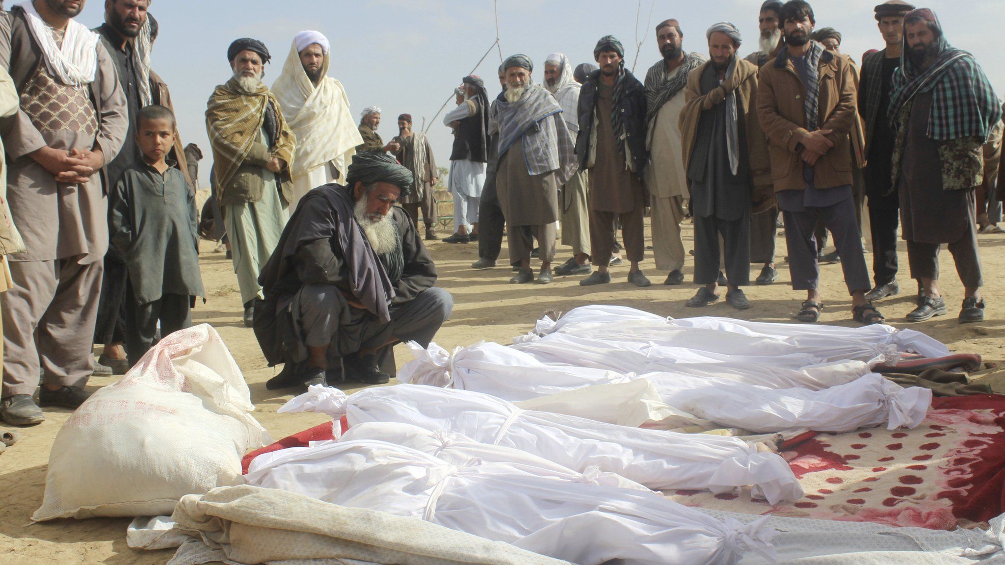 In this 4 November 2016 photo, Afghan villagers gather around several victims' bodies who were killed during clashes between Taliban and Afghan security forces in the Taliban-controlled, Buz-e Kandahari village in Kunduz province, Afghanistan
