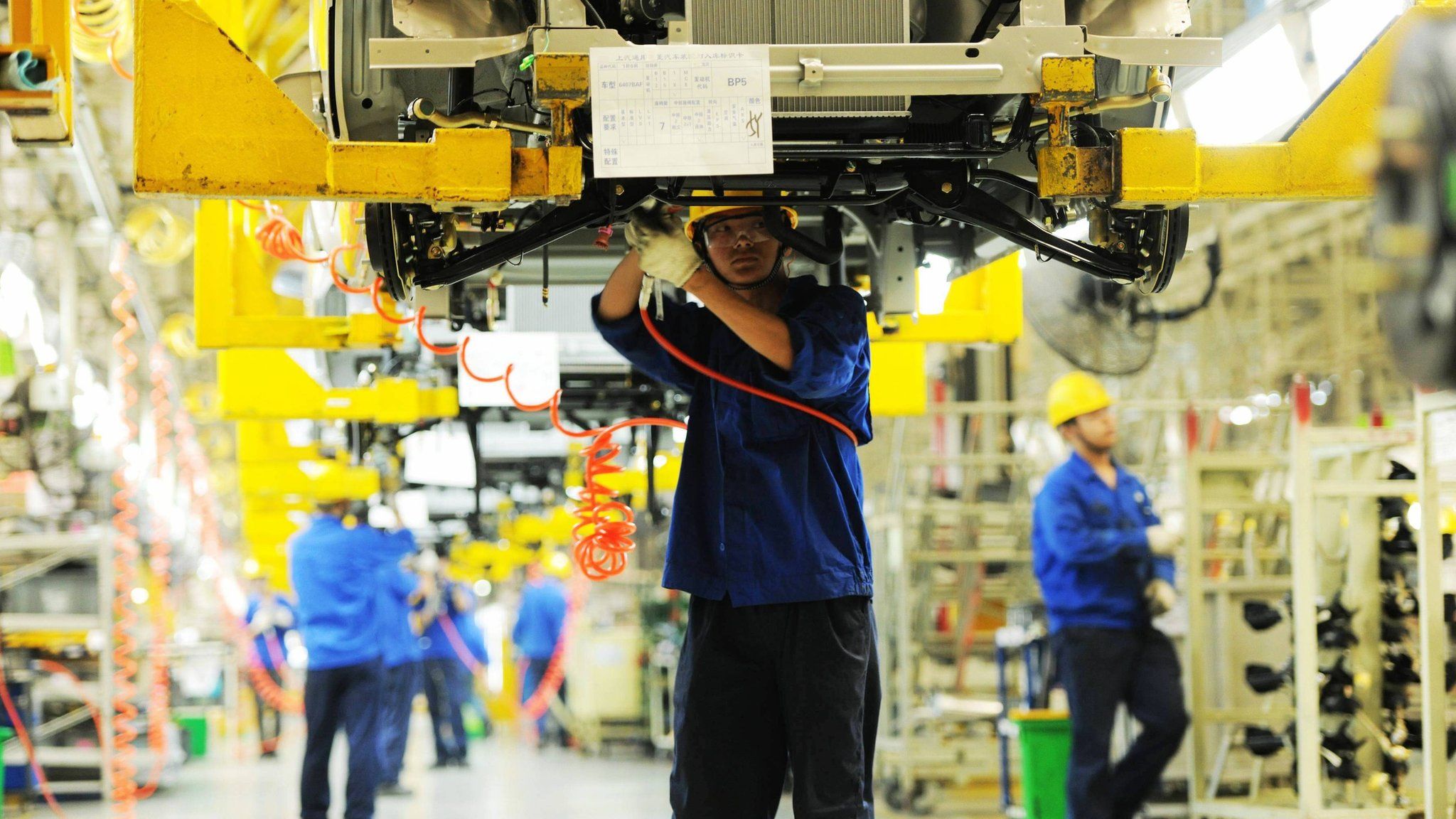 Workers install car parts at their assembly line in a factory in Qingdao, China