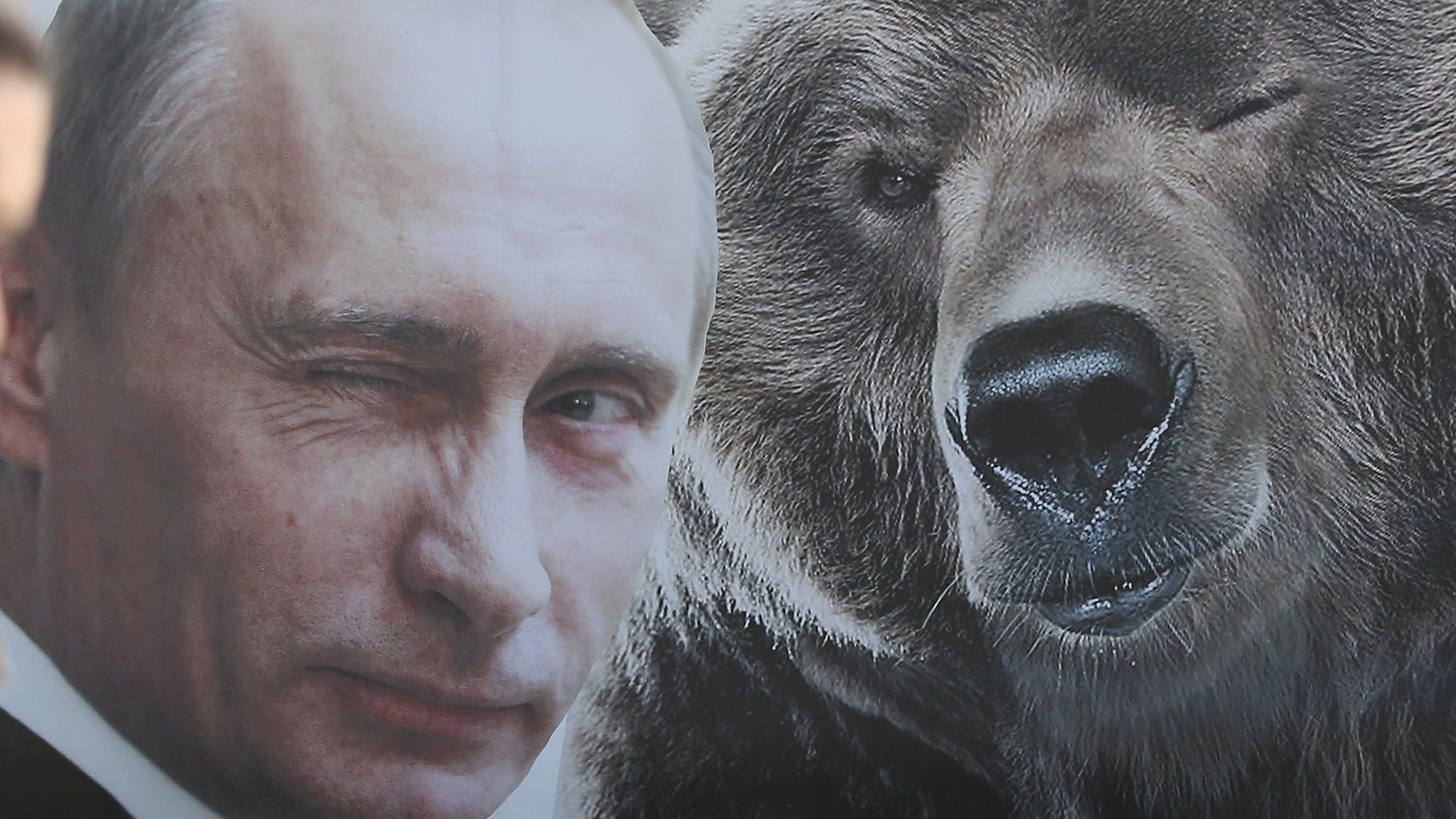 A woman walks past a portrait of a winking Russian President Vladimir Putin and a bear at Victory Park ahead of celebrations to mark the 70th anniversary of the victory over Nazi Germany and the end of World War II on May 8, 2015 in Moscow, Russia