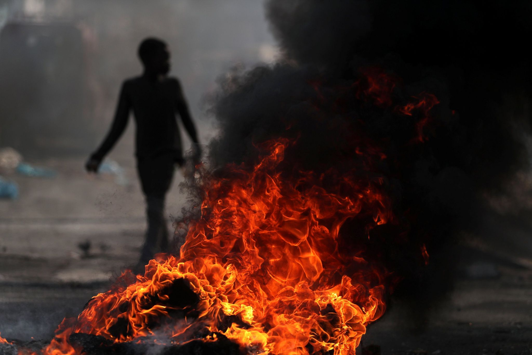 A child walks past a burning barricade during anti-government protests in Port-au-Prince