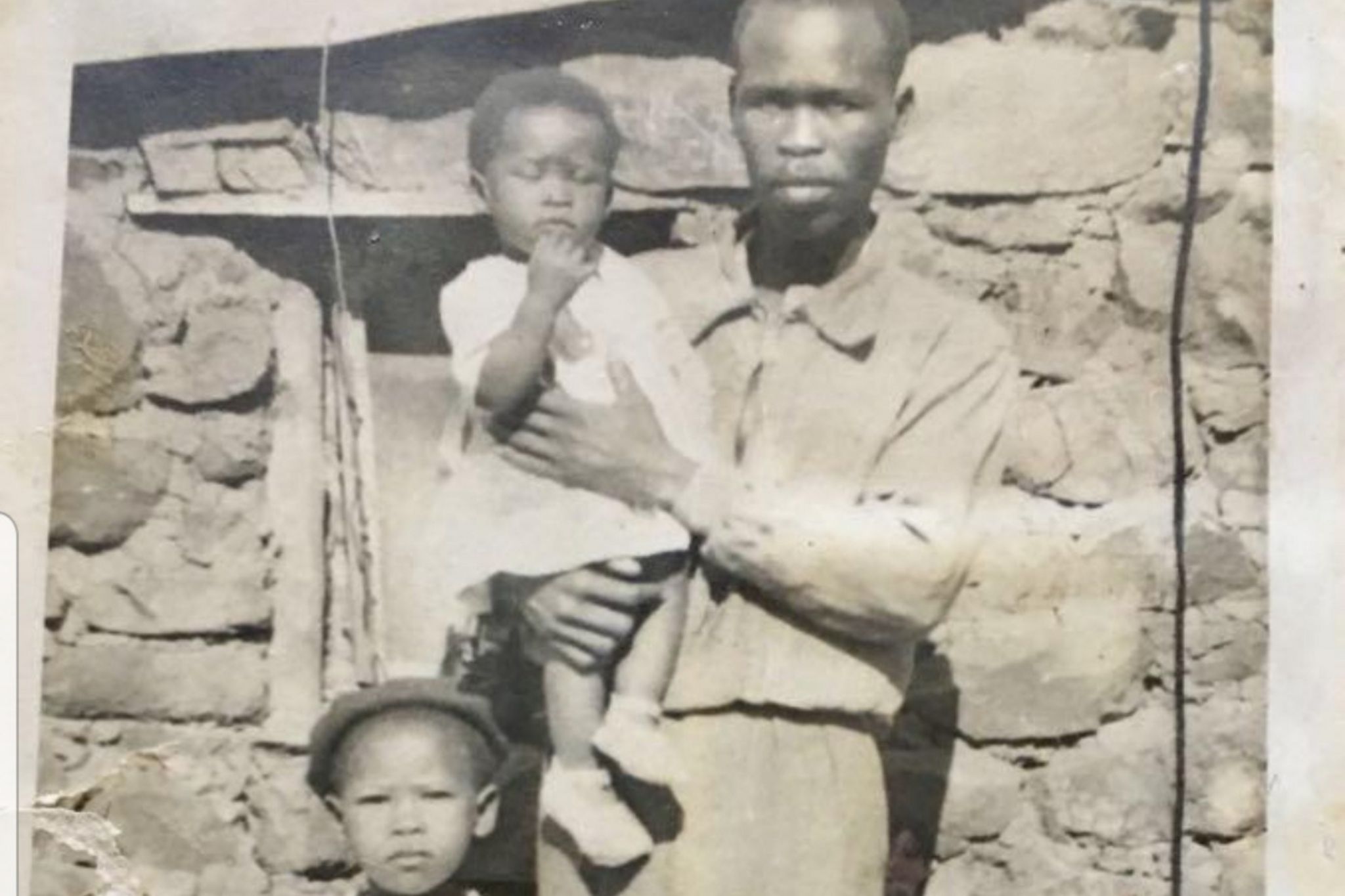 A photo of Agnes Sithole with her younger sister and father outside the house she was born in
