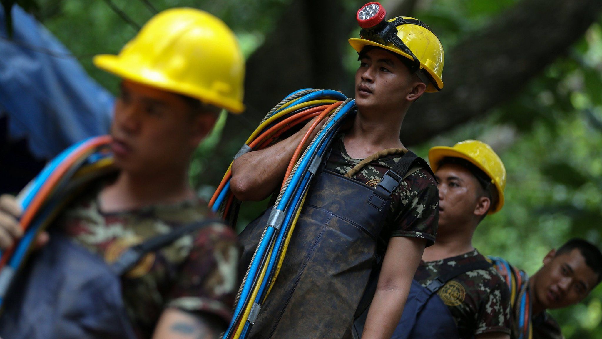Rescuers carry cables outside the Tham Luang cave complex in Thailand on 5 July 2018