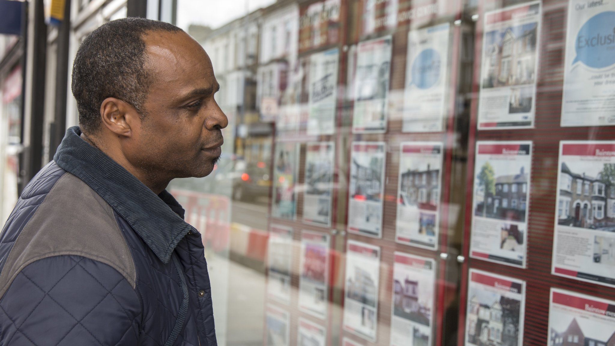 man looks in estate agent window