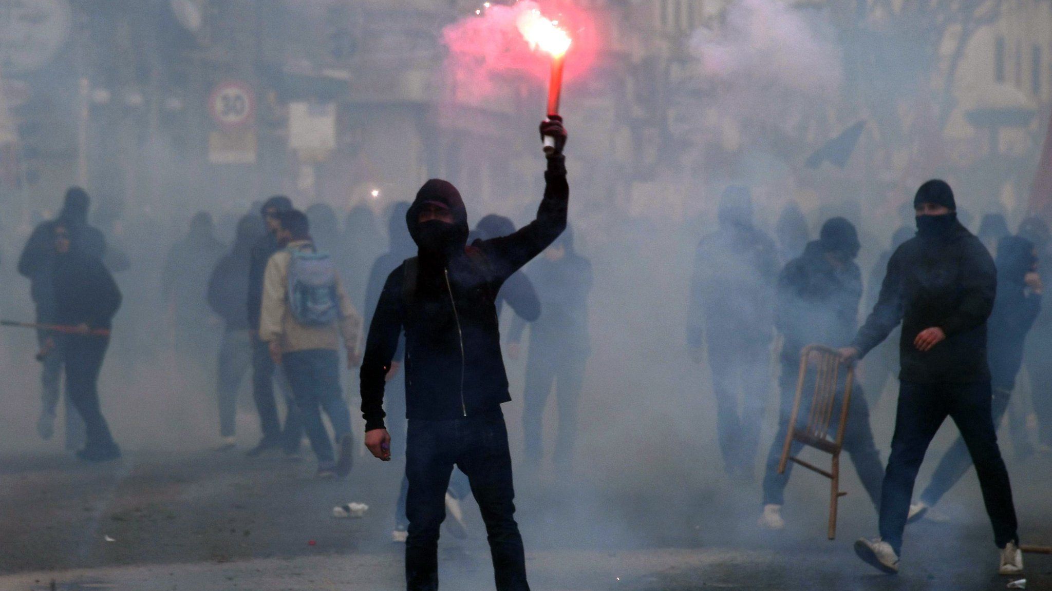A protester holds a flare during clashes with riot police at a demonstration against the visit of the leader of the Northern League party Matteo Salvini, in Naples, Italy, 11 March 2017