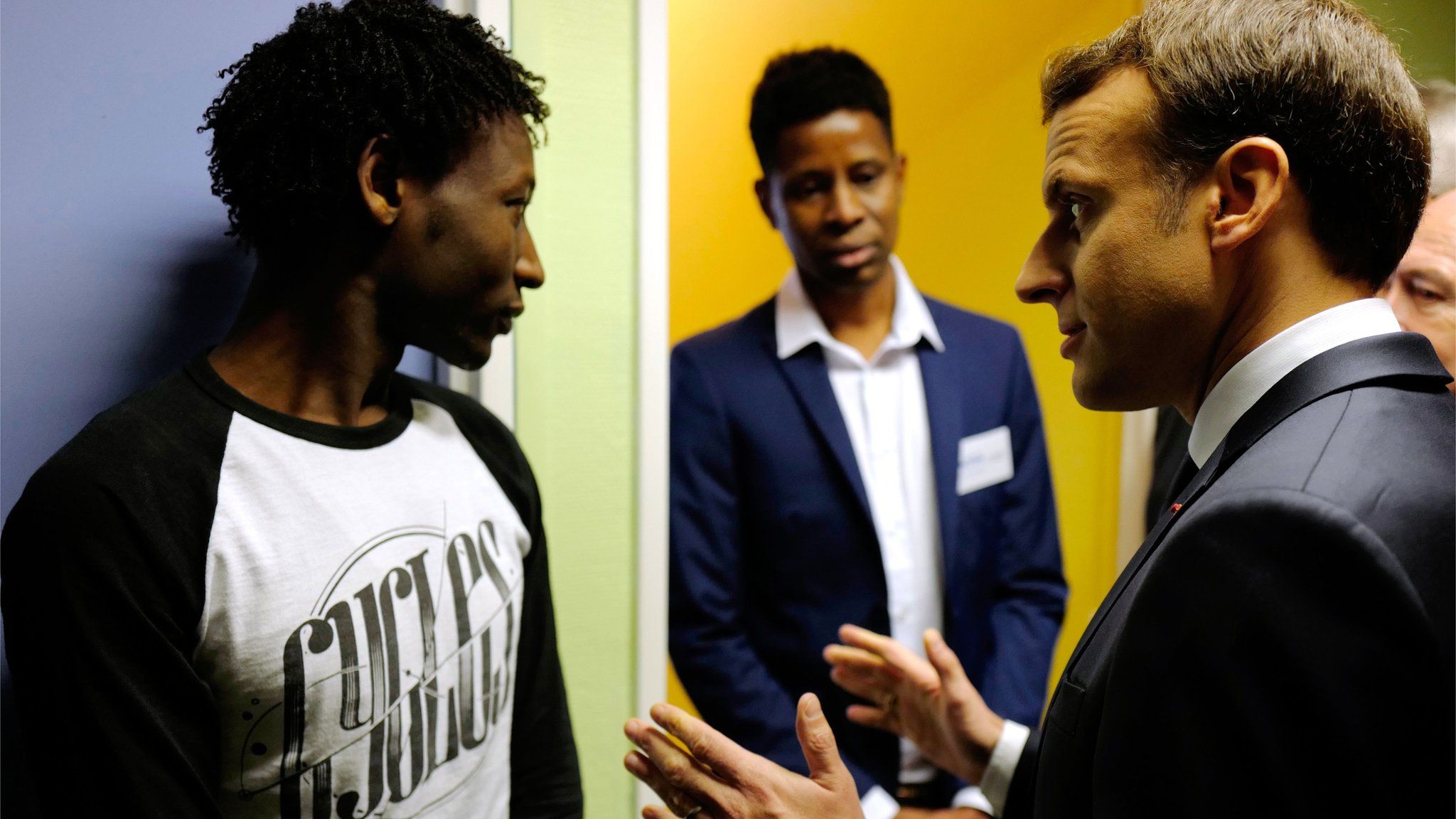 French President Emmanuel Macron speaks to a Sudanese migrant in Calais