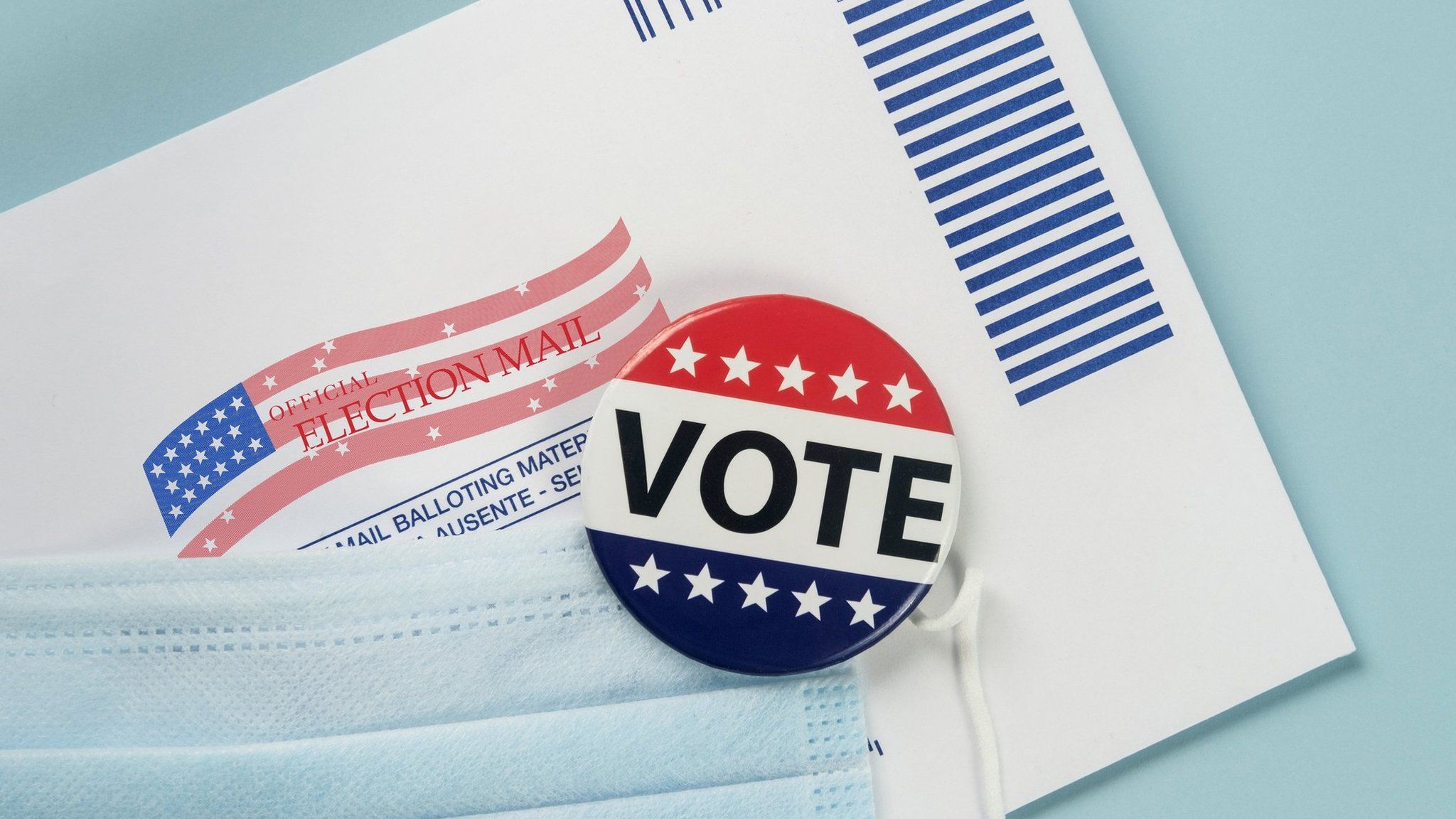 A US postal ballot, a badge saying "VOTE" and a face mask