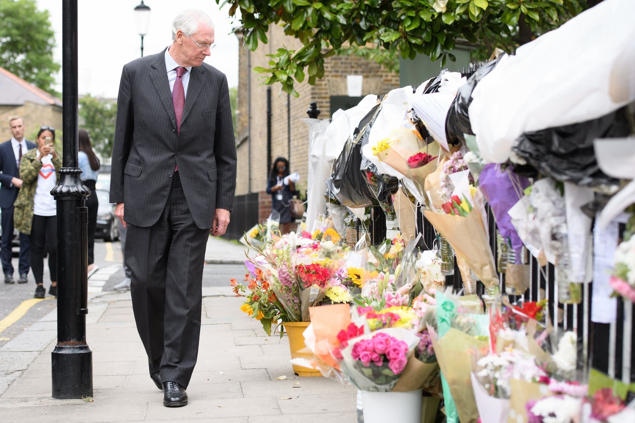 Sir Martin Moore-Bick looks at flowers at a Grenfell tribute