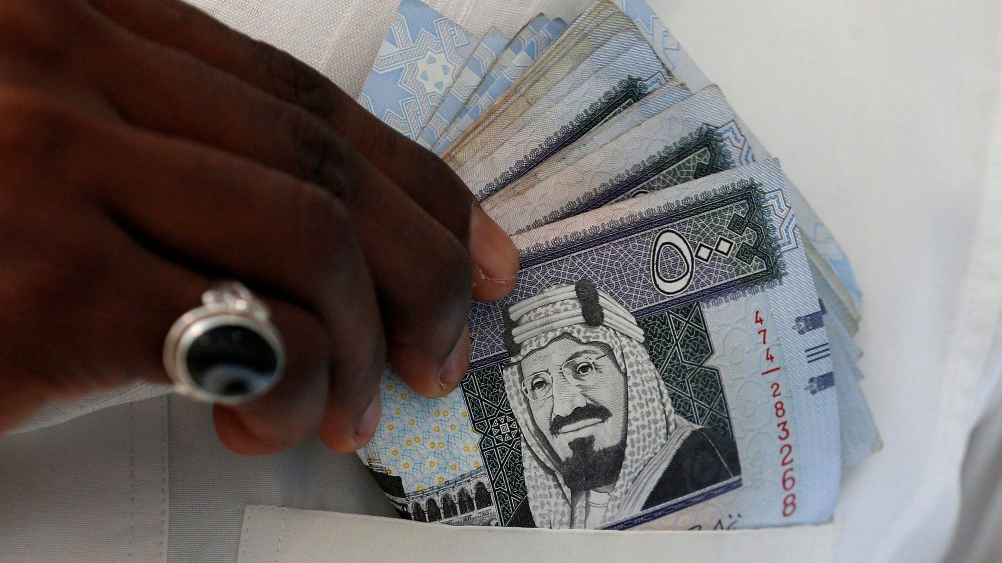 A Saudi man shows Saudi riyal banknotes at a money exchange, in Riyadh, Saudi Arabia (30 January 2016)