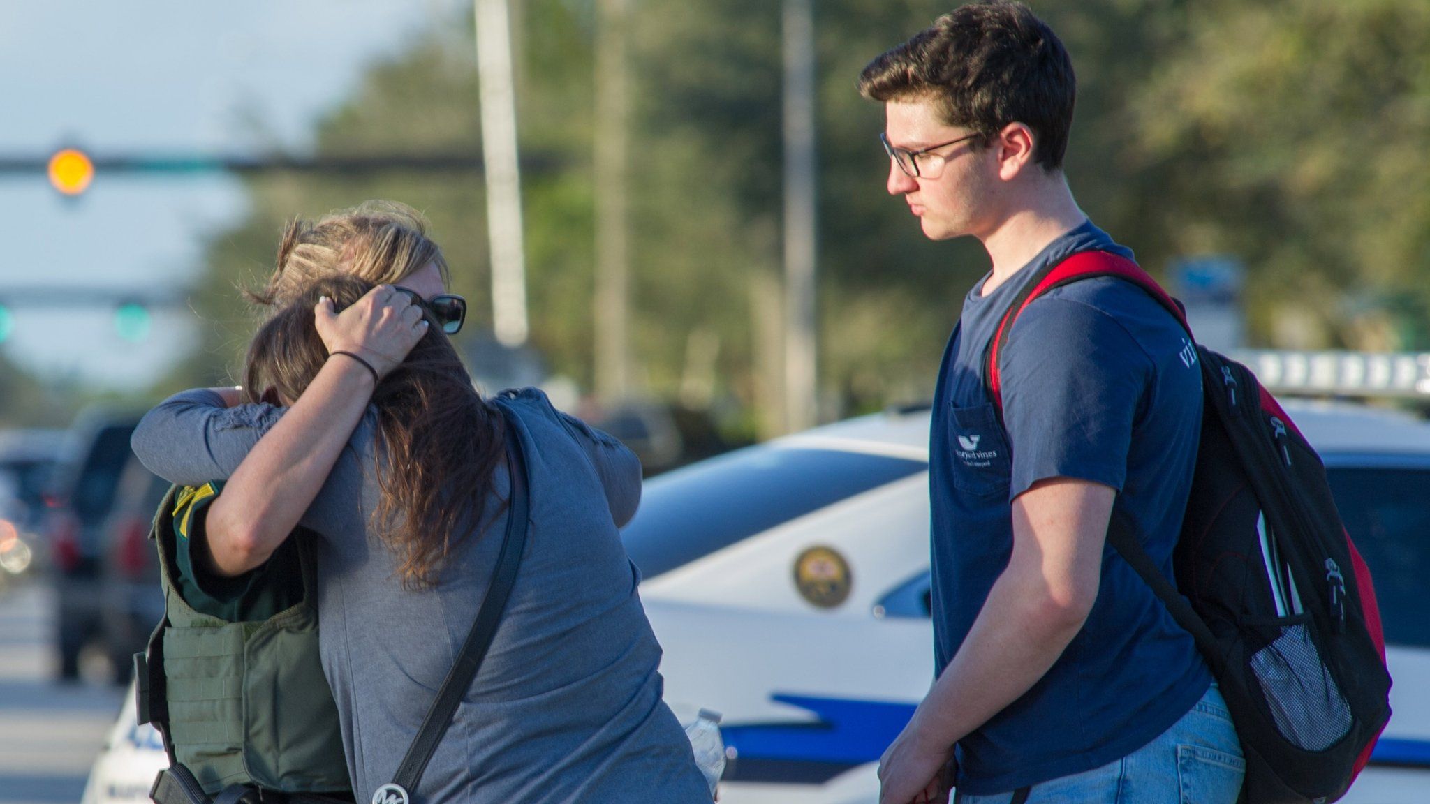 Woman comforted by police officer outside Marjory Stoneman Douglas High School in Parkland, Florida, on 14 February 2018