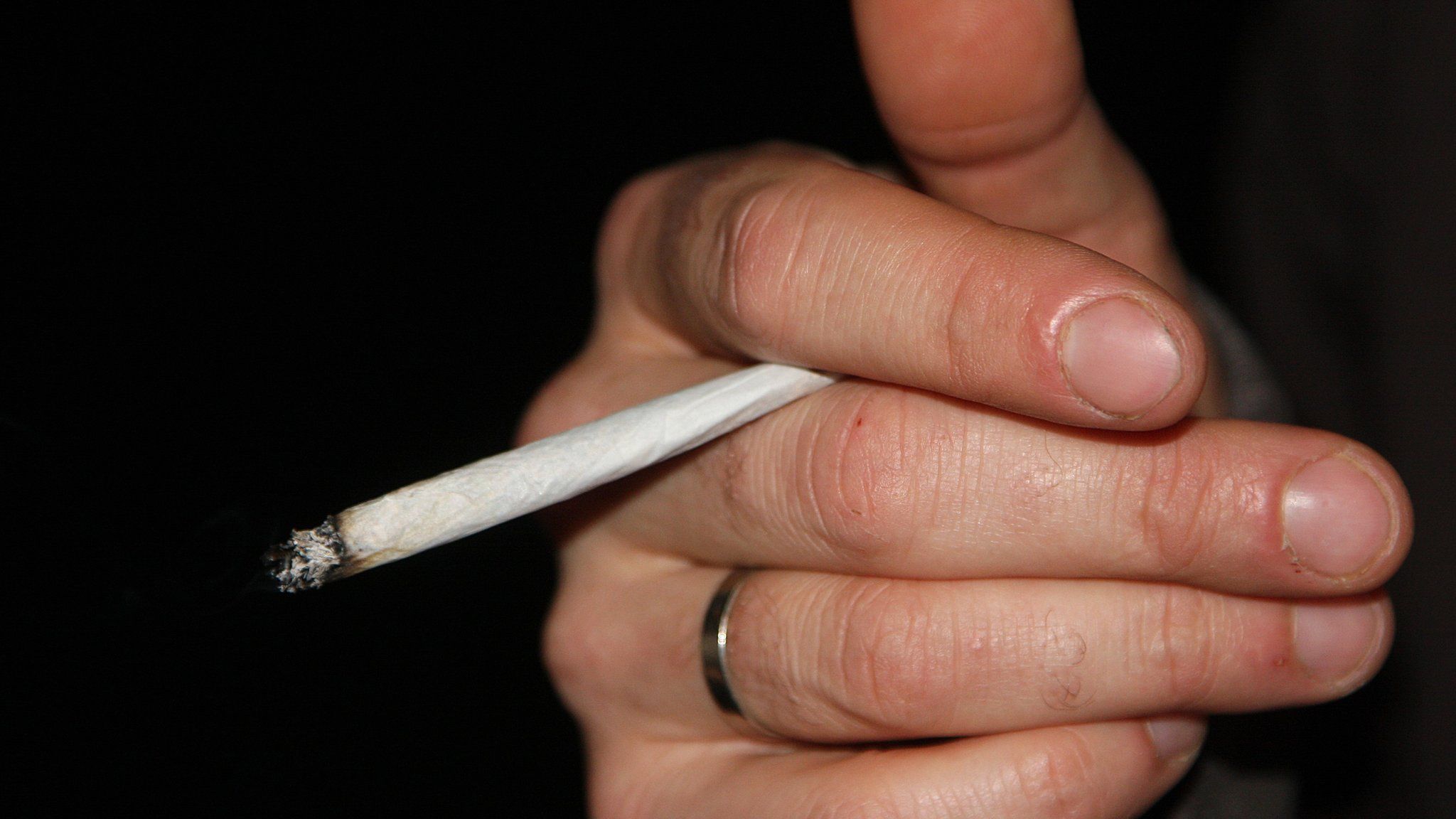 A hand holding a rolled cigarette