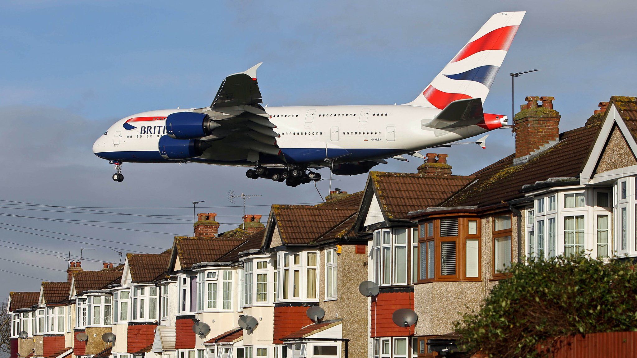 A plane over rooftops next to Heathrow airport
