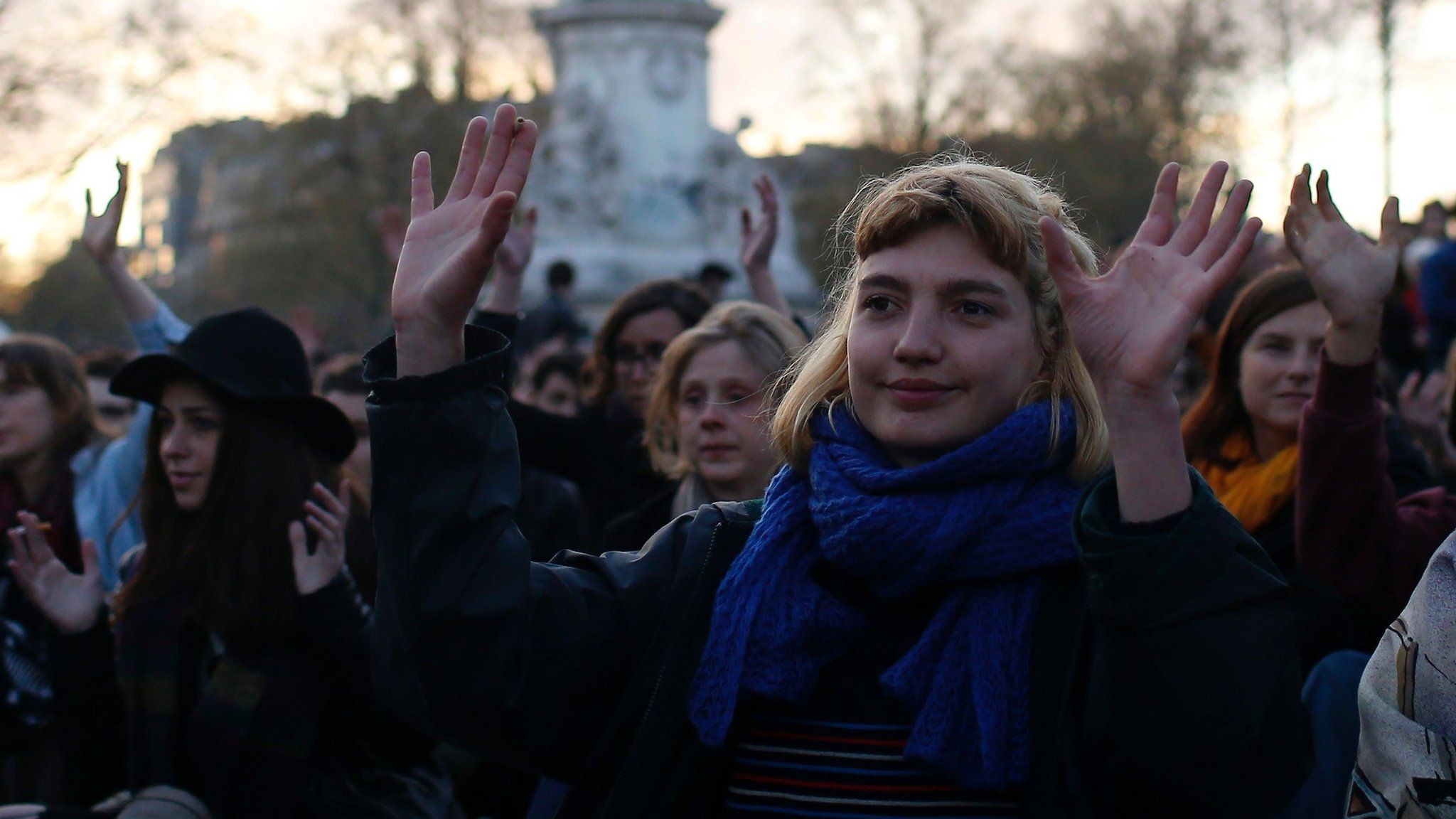 People gesture as they listen to a speech during a gathering by the 'Nuit Debout' movement on Place de la Republique in Paris