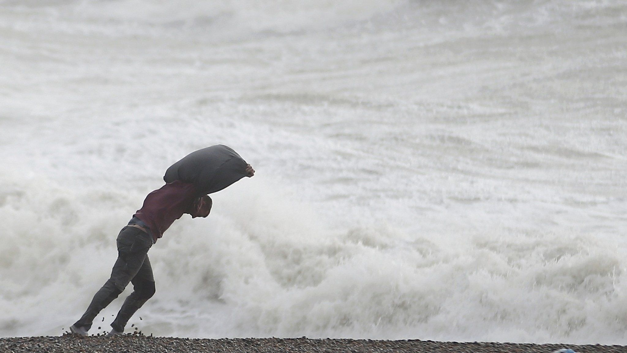 A man leans into the wind on the beach at Newhaven, southern England